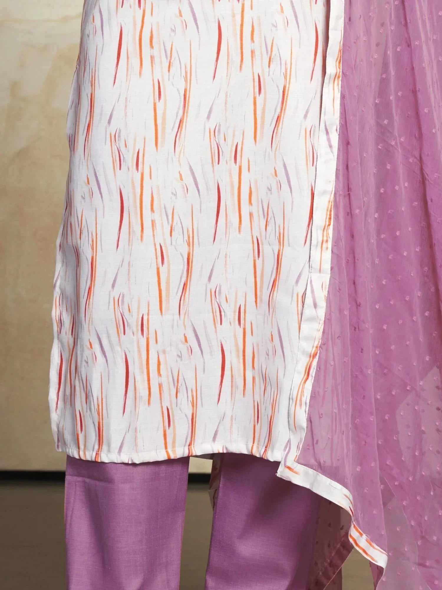 White kurta with orange and purple patterns, paired with lavender pants and dupatta