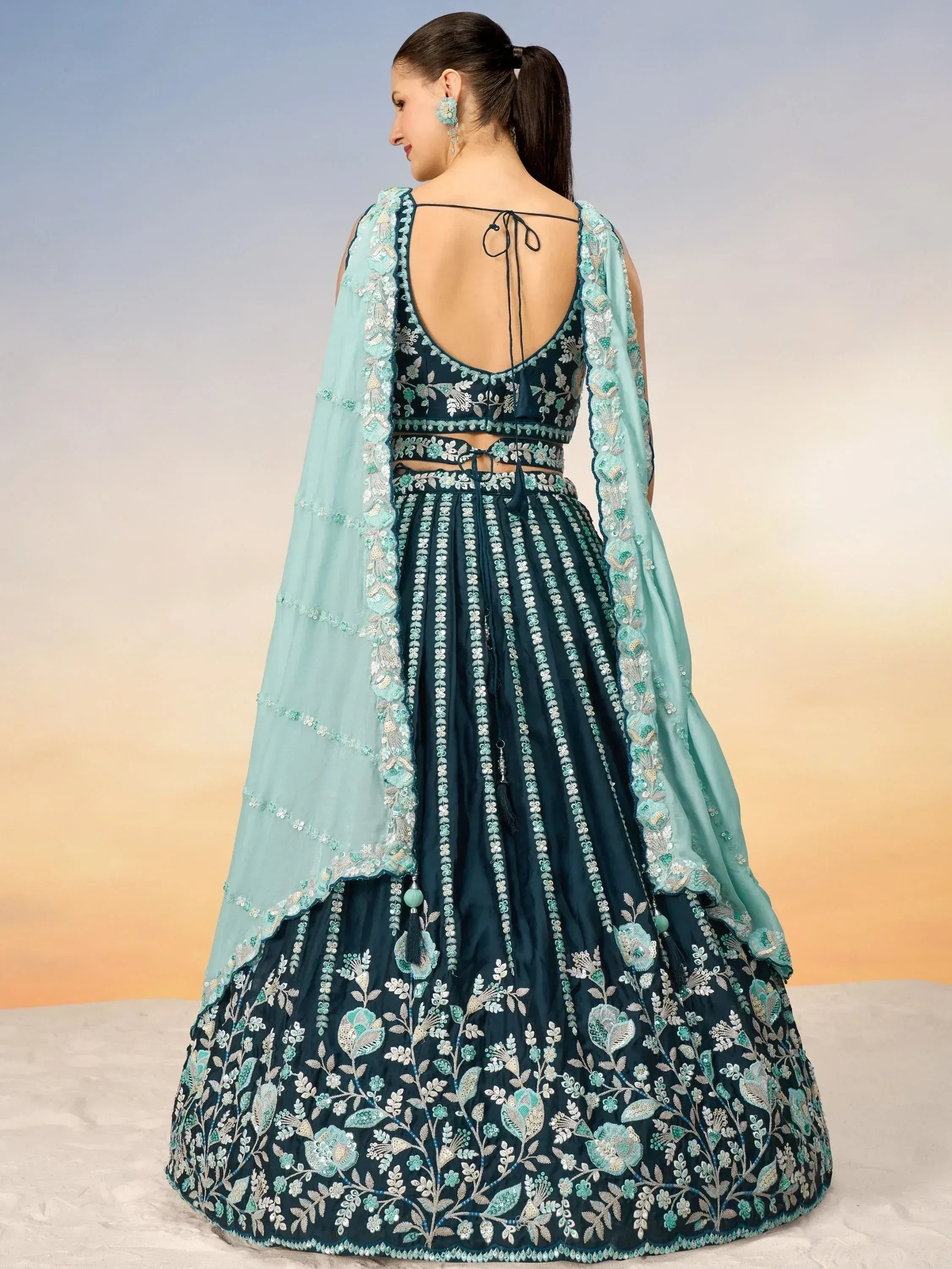 Dark teal embroidered lehenga choli with floral motifs and sheer mint dupatta, back view