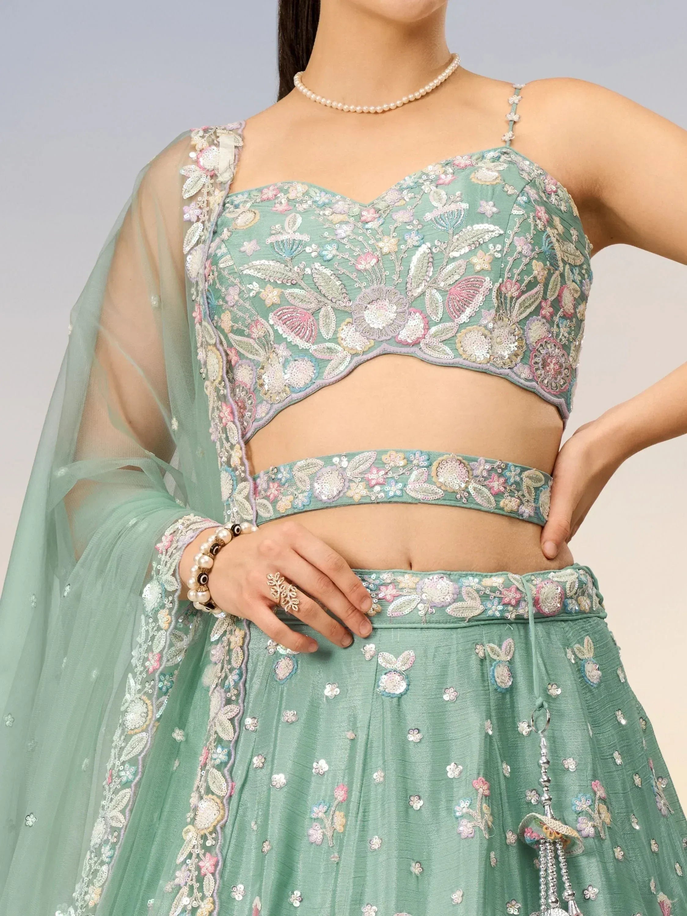 Mint green embroidered lehenga choli with floral sequin work, sheer dupatta, and pearl jewelry