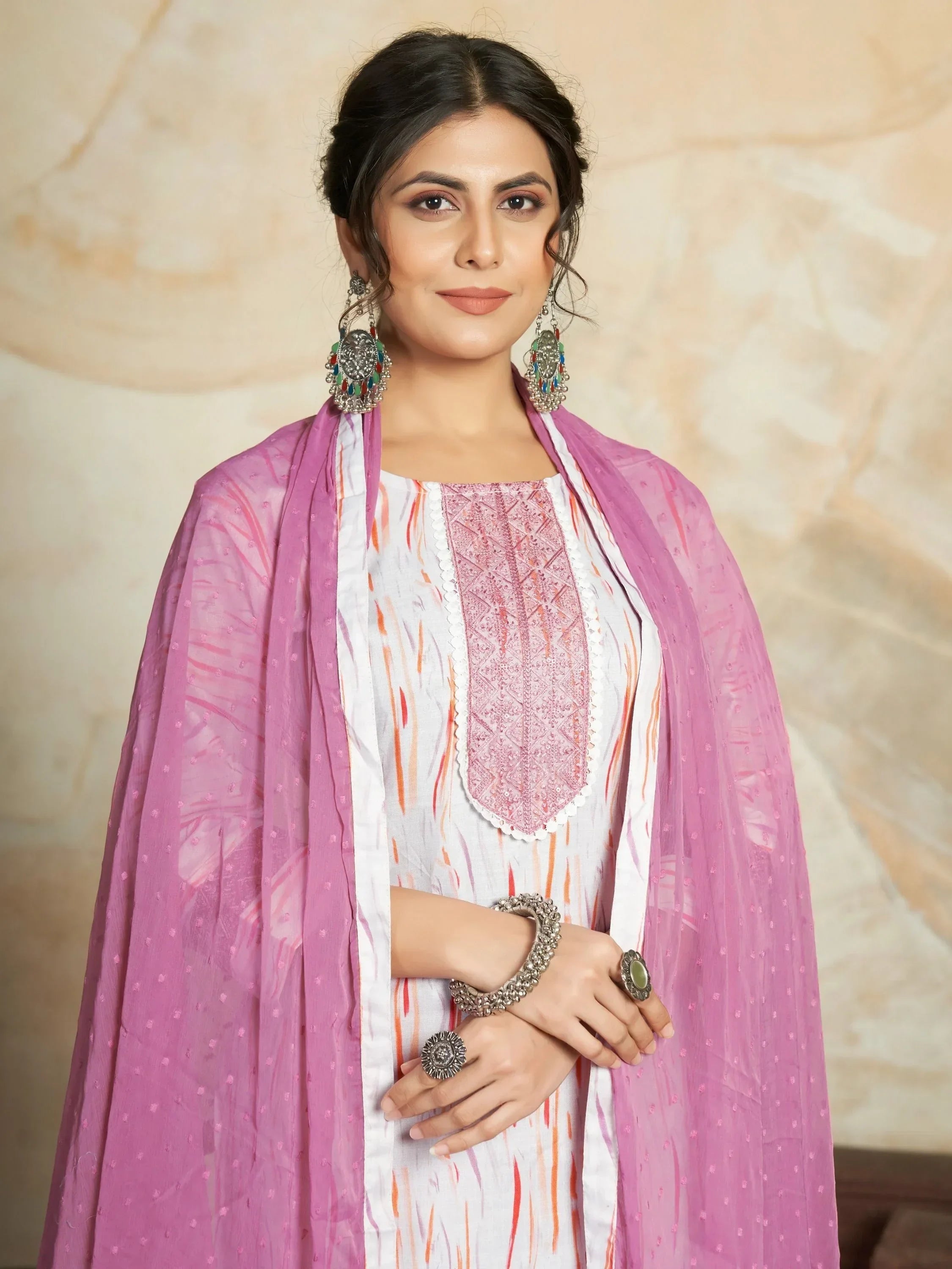 Woman in a white and pink printed salwar kameez with matching dupatta and ethnic jewelry