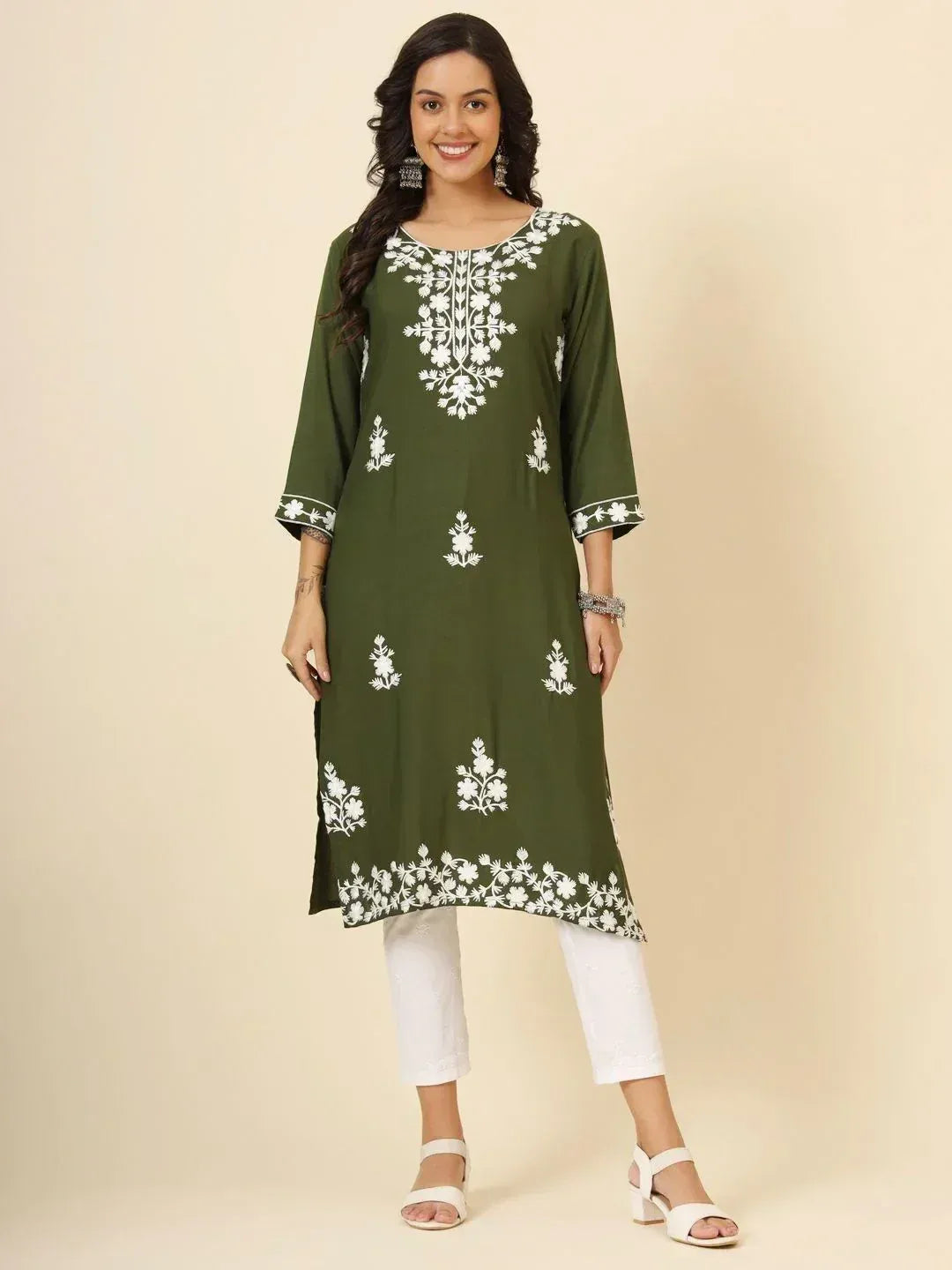 Woman wearing olive green embroidered kurti with white floral patterns and white pants