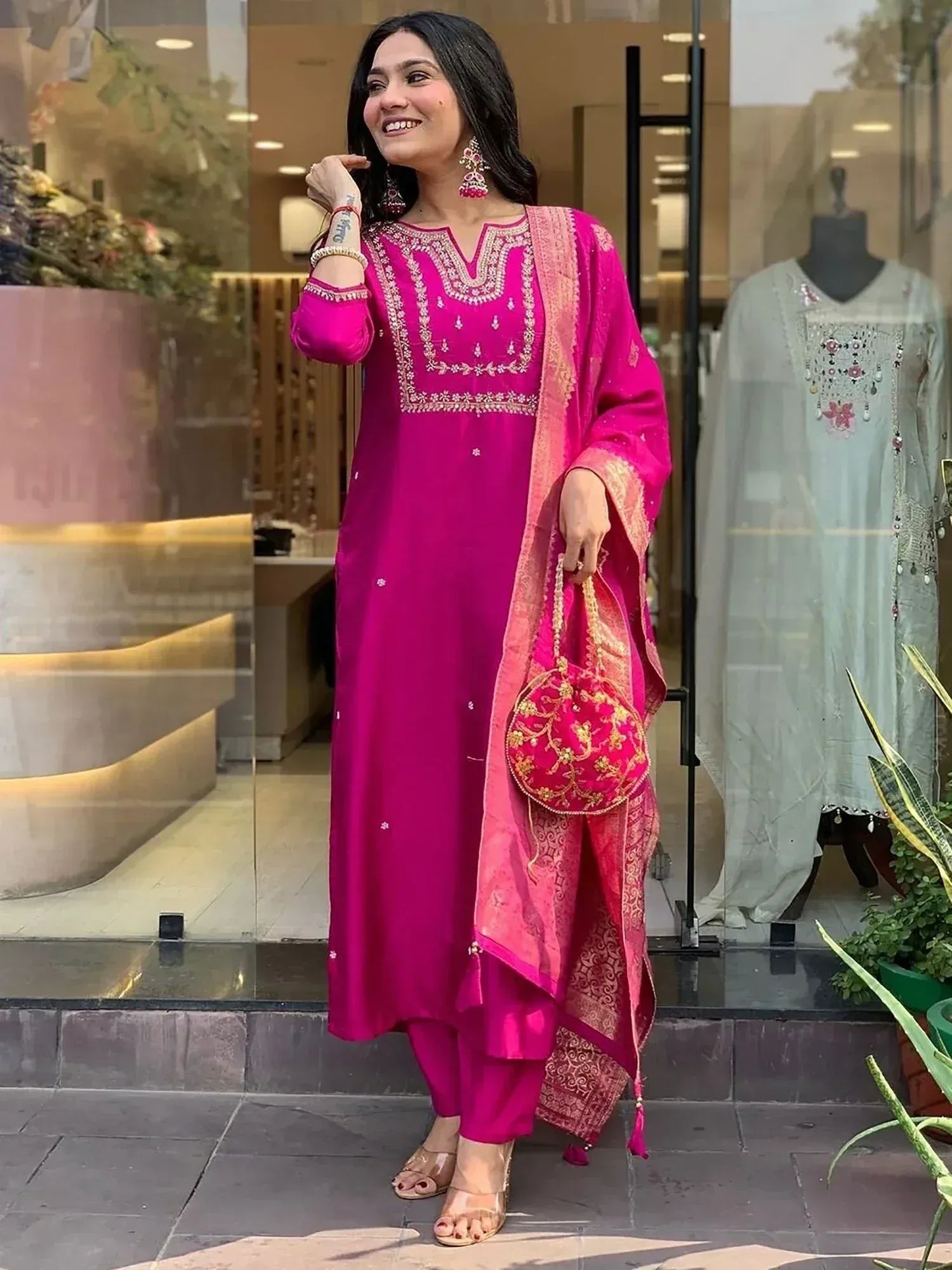 Vibrant pink embroidered salwar kameez with matching dupatta and potli bag, perfect for festive occasions.