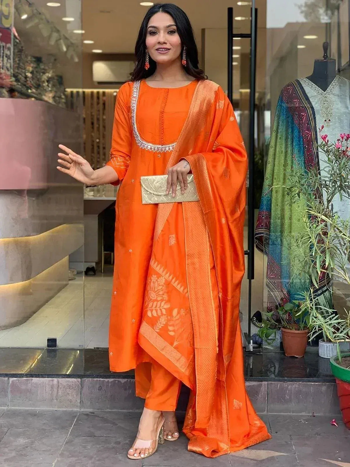 Vibrant orange ethnic salwar kameez with embroidered neckline and printed dupatta, perfect for festive occasions.