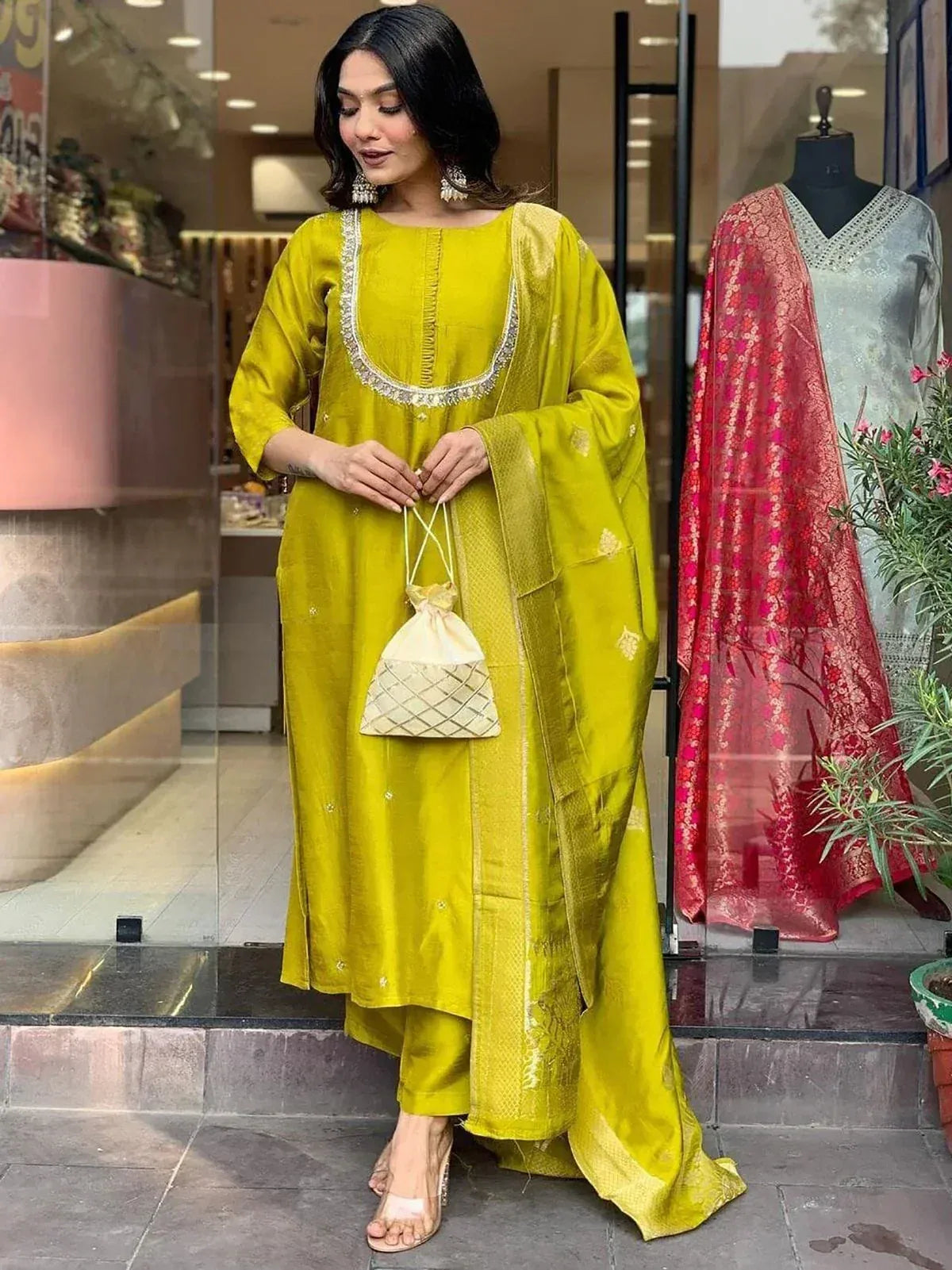 Yellow ethnic salwar kameez with embroidered neckline and matching dupatta, styled with potli bag