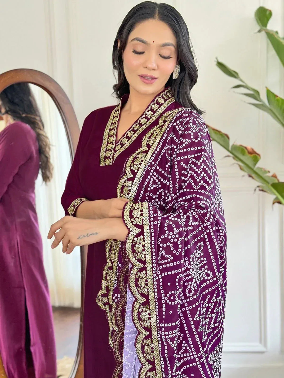 Purple velvet ethnic gown with gold embroidery and white print, styled with mirror and greenery