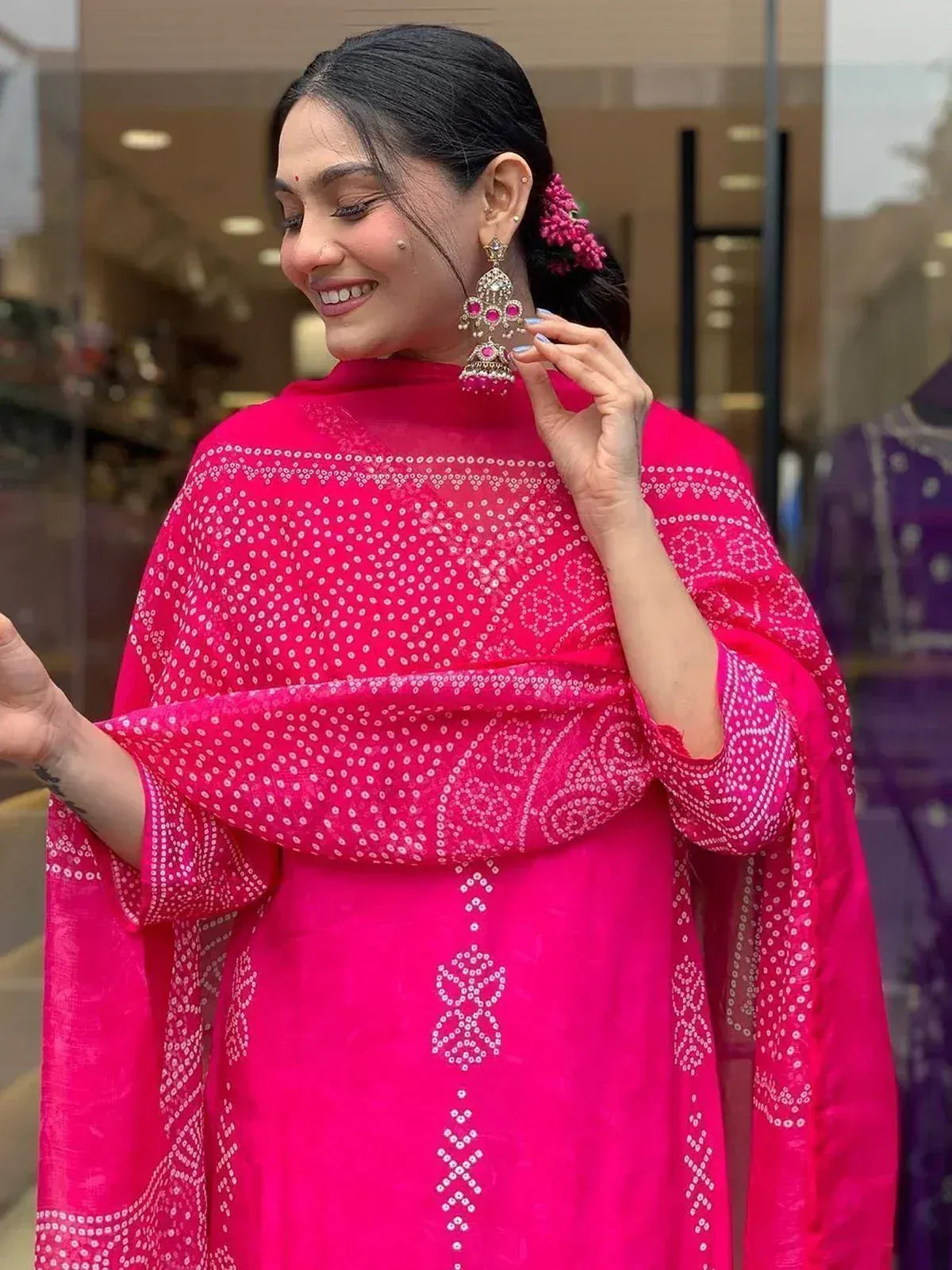 Woman in vibrant pink ethnic kurta with white embroidery and matching dupatta, accessorized with jhumka earrings