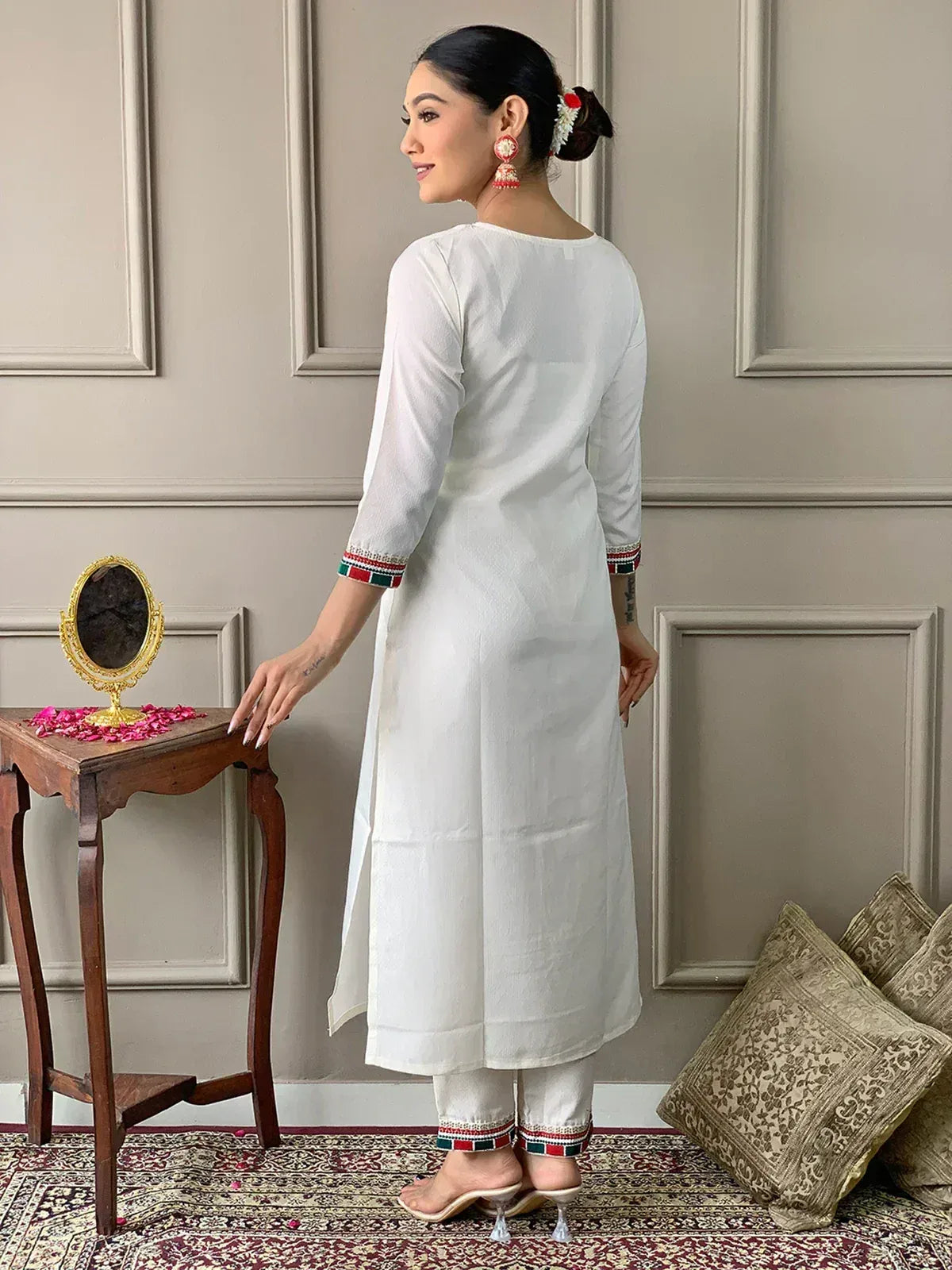 White ethnic kurta with colorful embroidered cuffs and matching pants, styled with traditional earrings