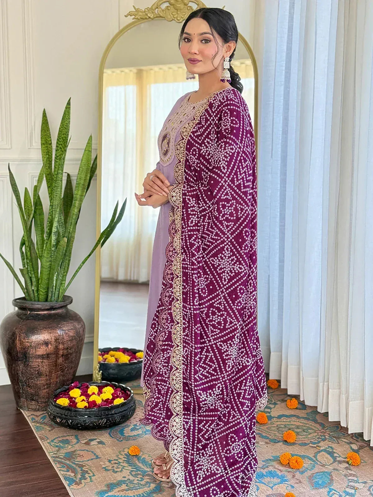 Woman in purple embroidered ethnic gown with gold detailing, floral decor, and mirror backdrop