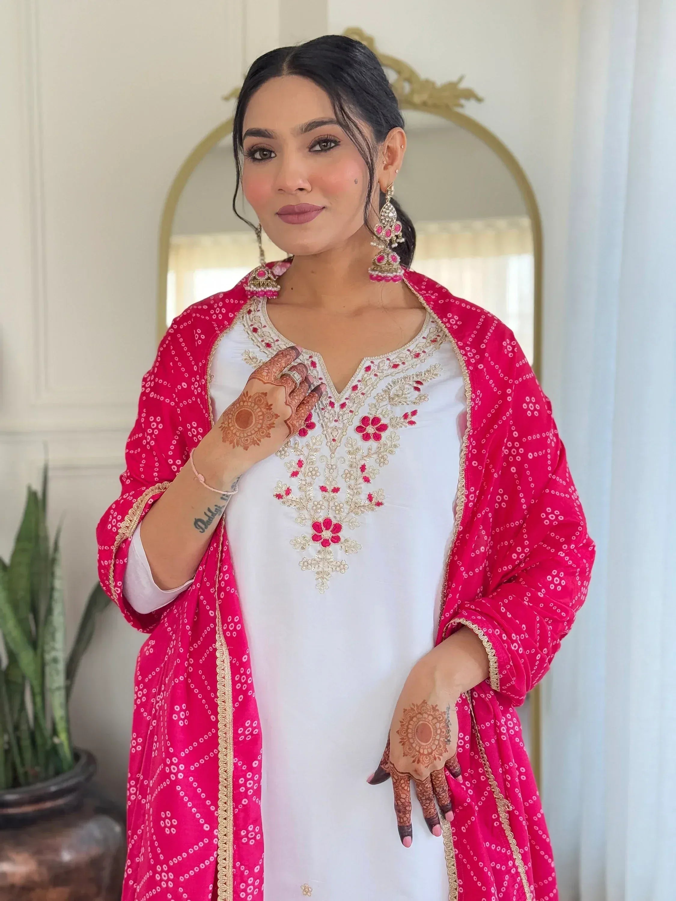 White embroidered kurta with pink dupatta, henna designs, and traditional earrings