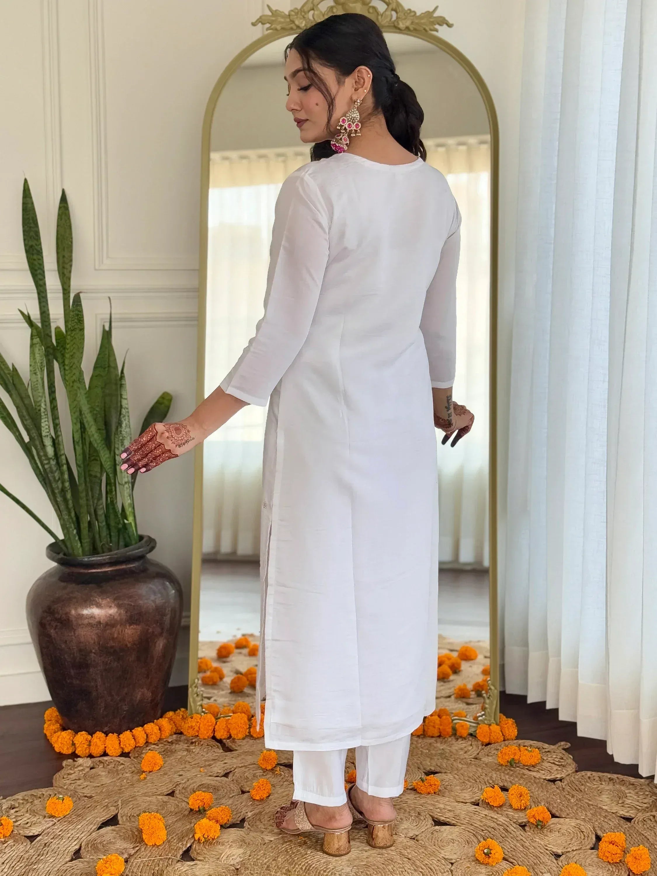 White ethnic kurta with henna hands, marigold flowers, and mirror backdrop