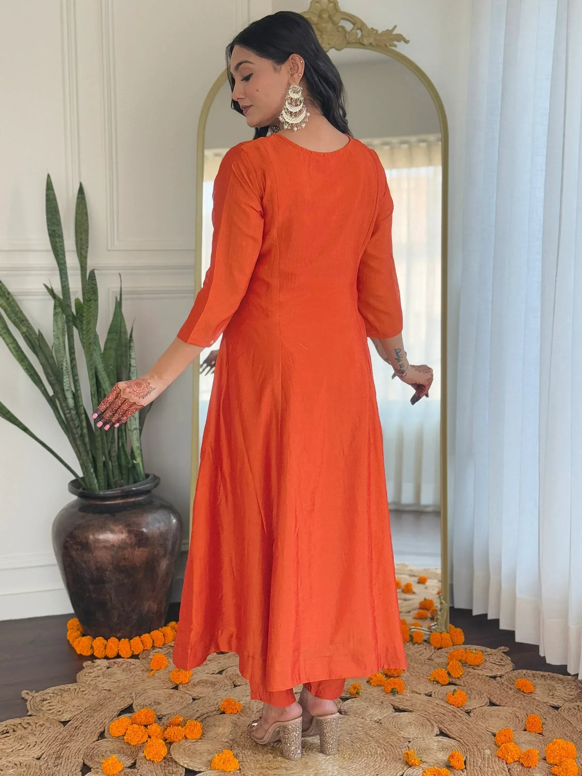 Orange ethnic gown with henna designs, marigold flowers, and mirror backdrop