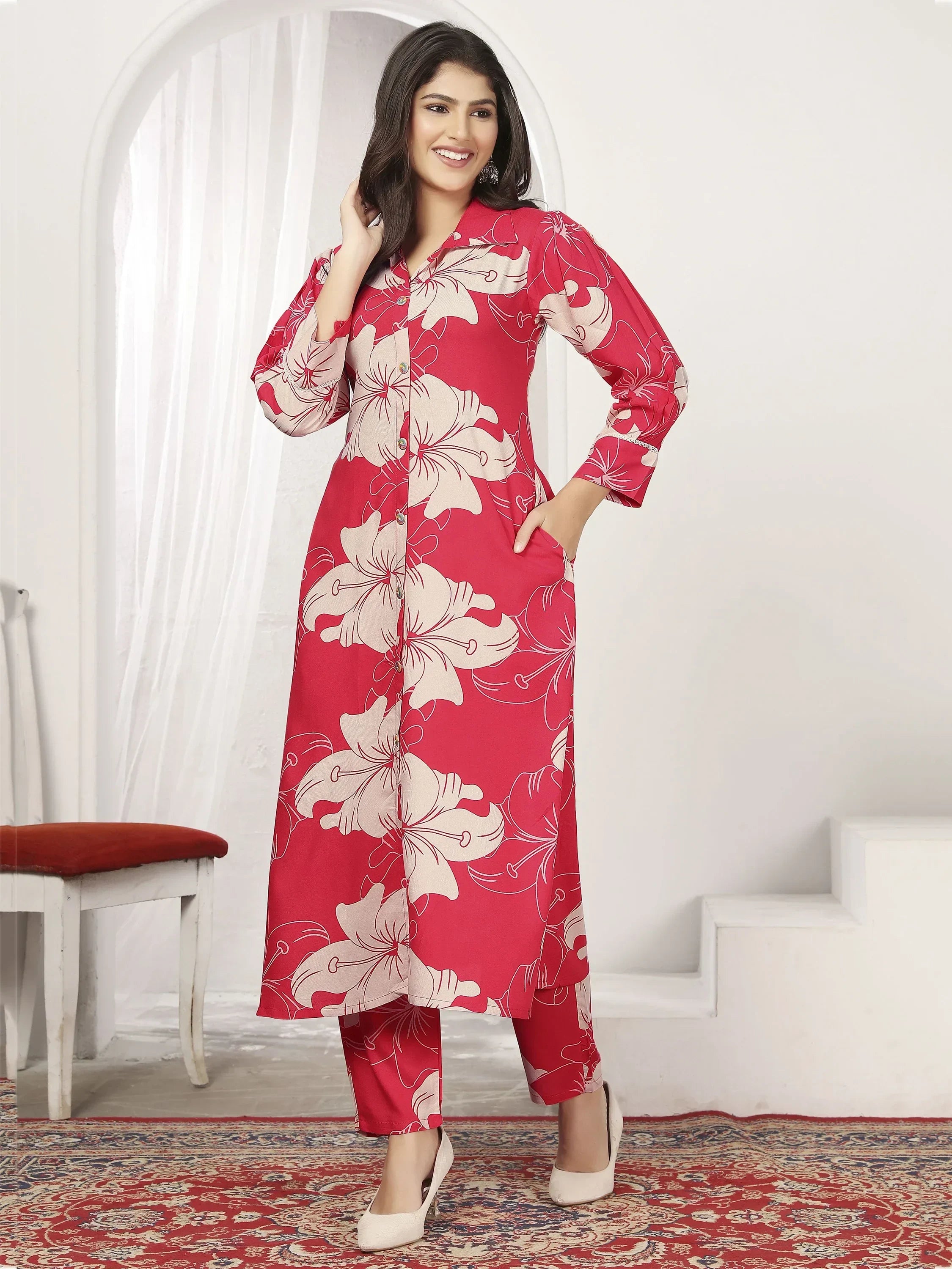 Woman wearing red floral printed kurta set with straight pants, standing indoors