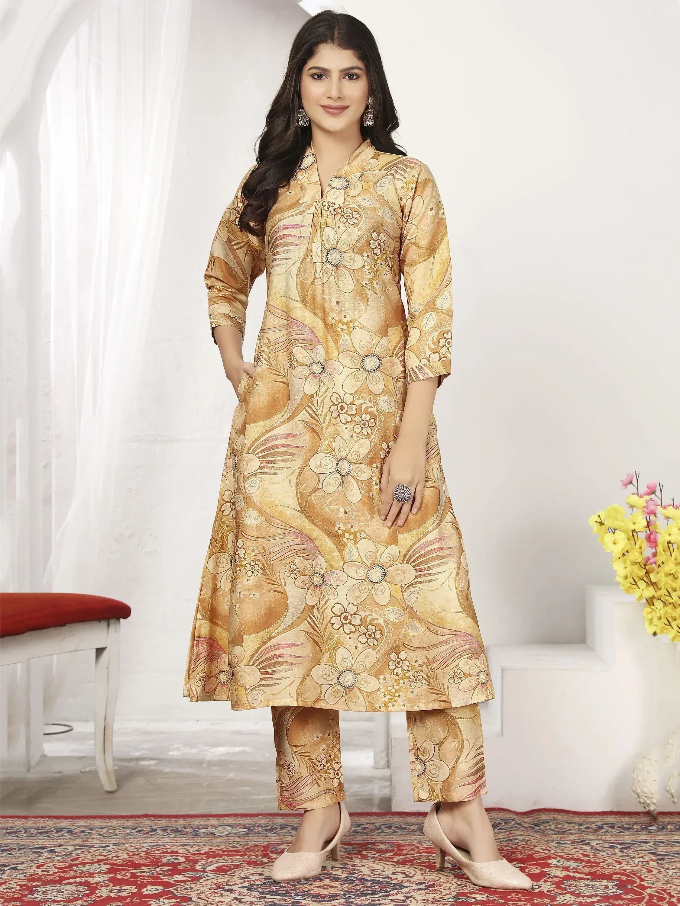 Woman in gold floral print salwar kameez, ethnic Indian wear with matching pants and heels