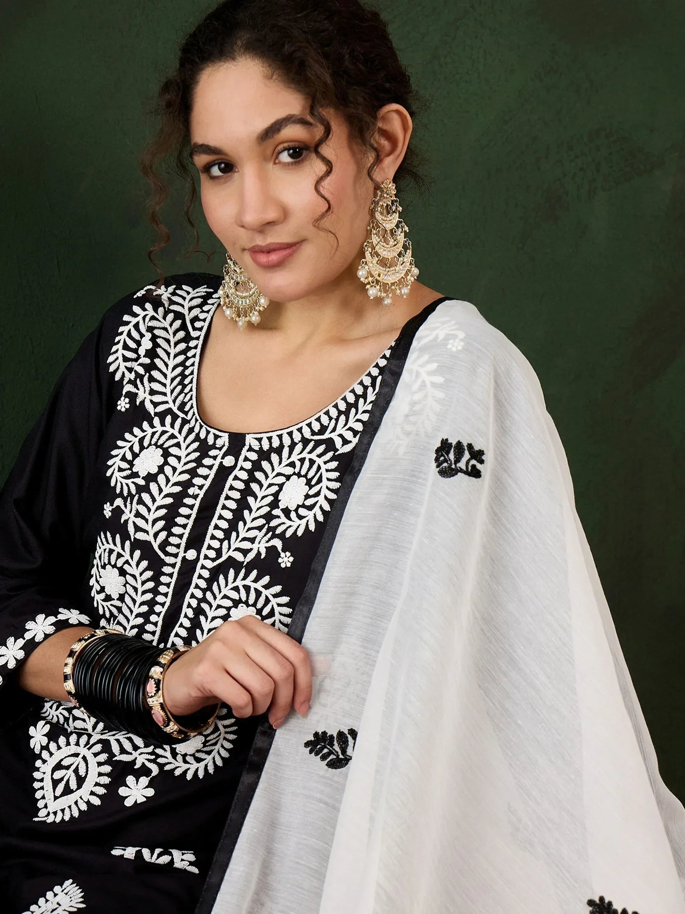 Black and white embroidered salwar kameez with floral patterns, paired with statement earrings and bangles.