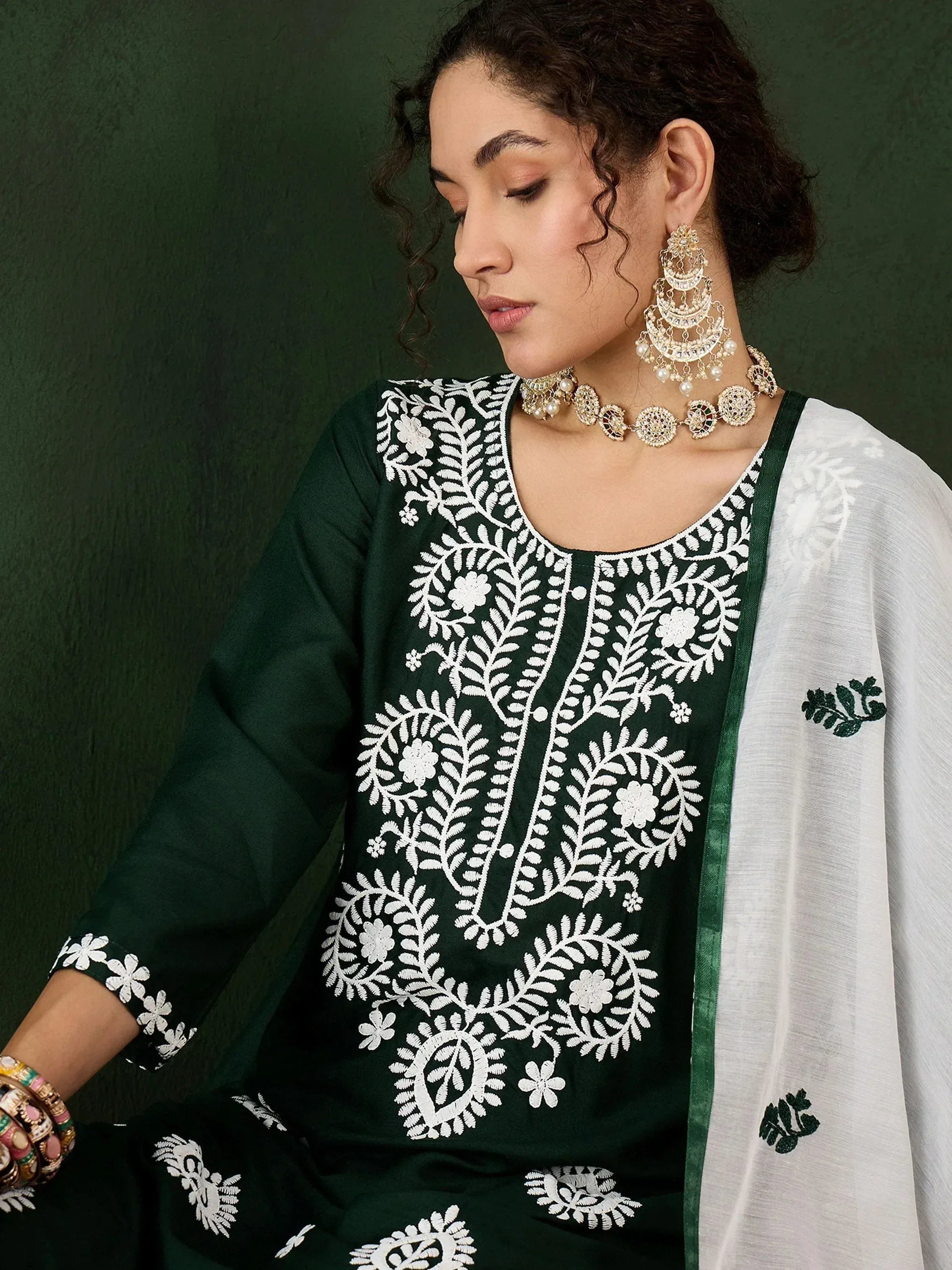Green embroidered salwar kameez with white floral work, paired with statement jewelry for ethnic wear.