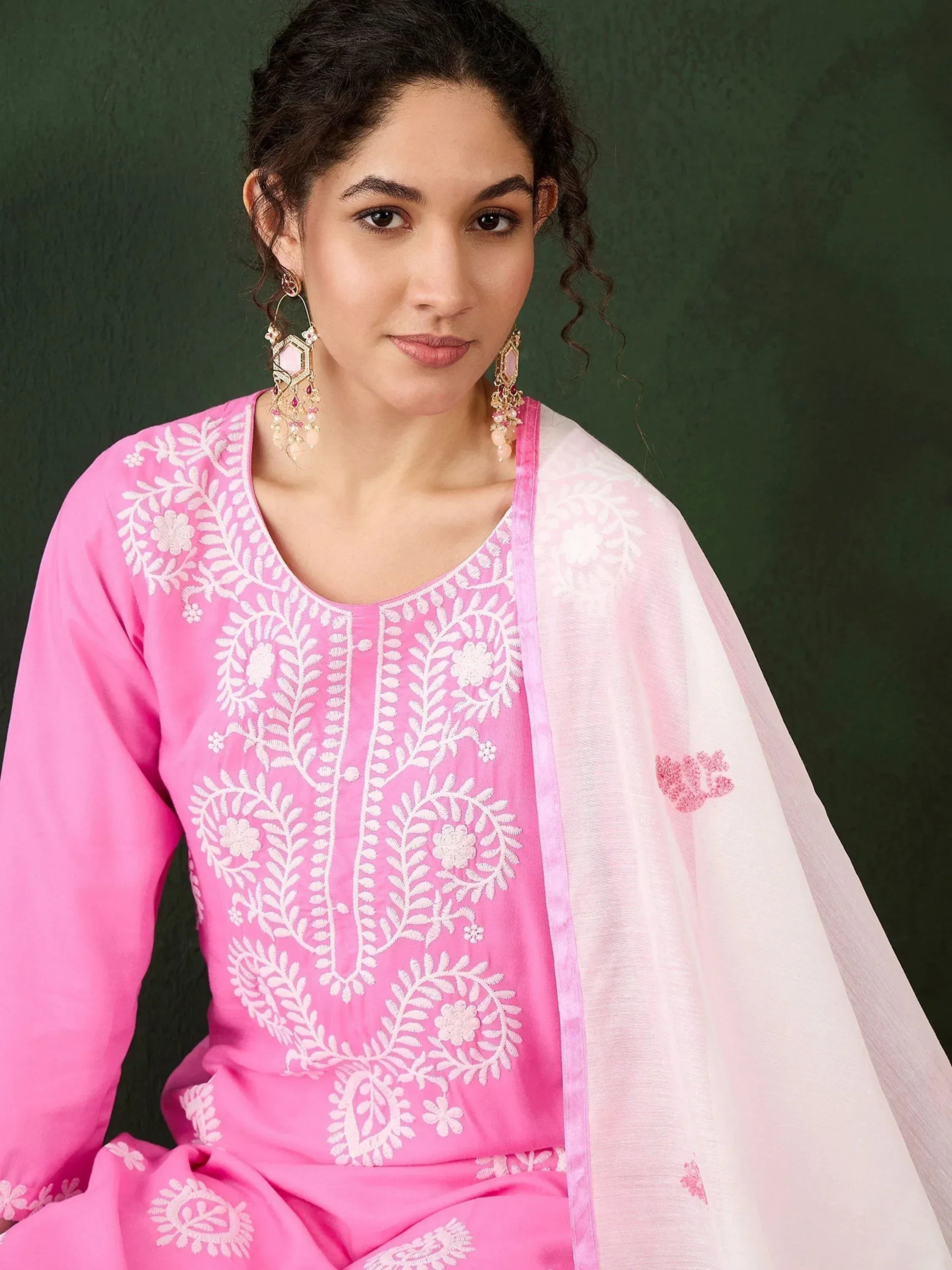 Pink embroidered salwar kameez with white floral work and matching dupatta, styled with statement earrings