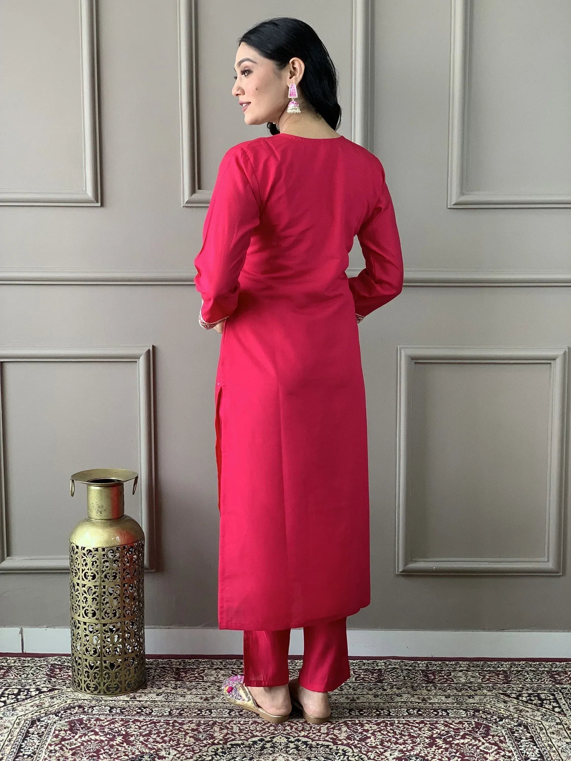 Woman in vibrant pink Indian ethnic kurta with matching pants, showcasing back view and side slit