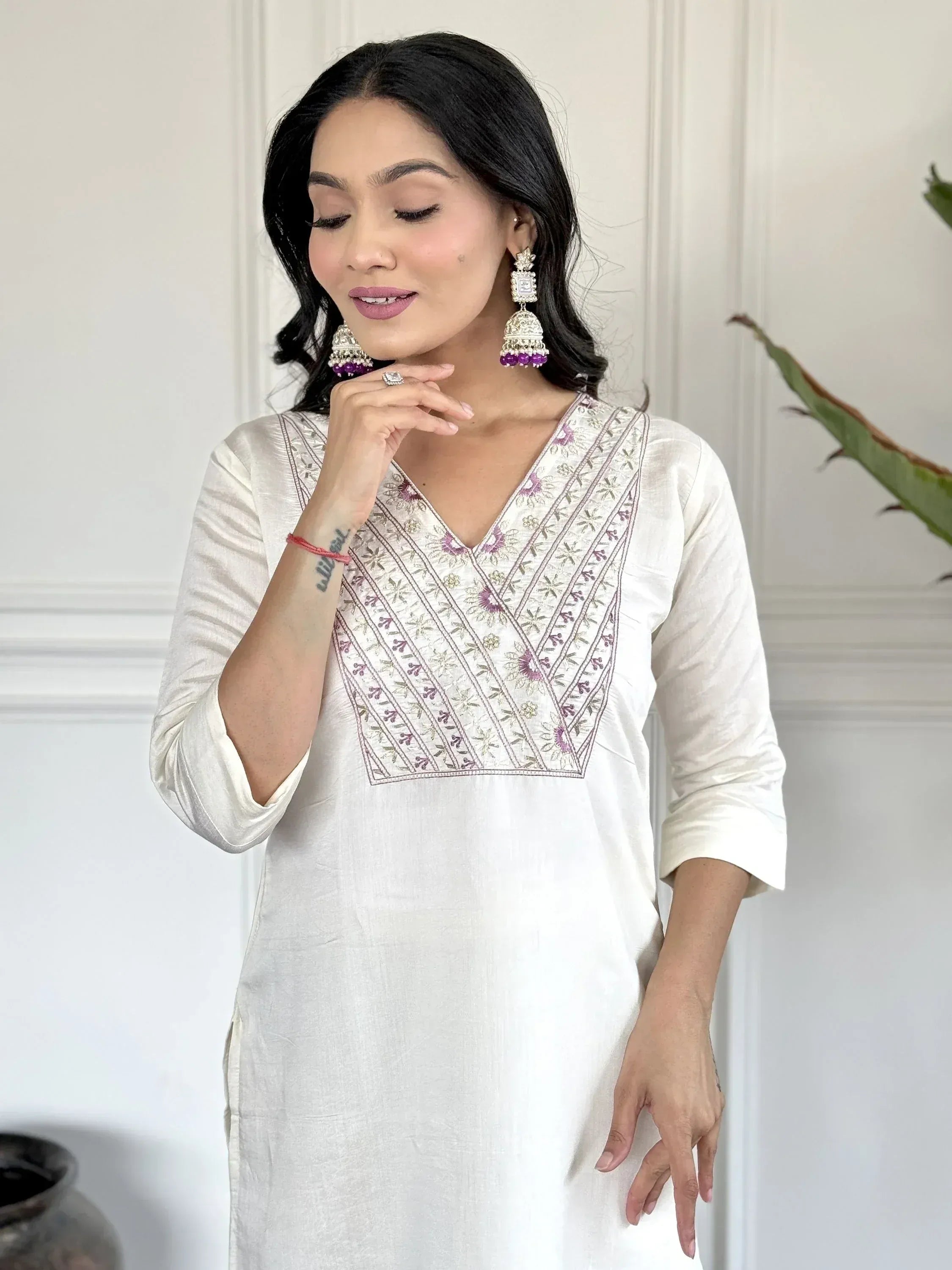 White embroidered kurta with purple floral detailing, paired with statement jhumka earrings for ethnic wear