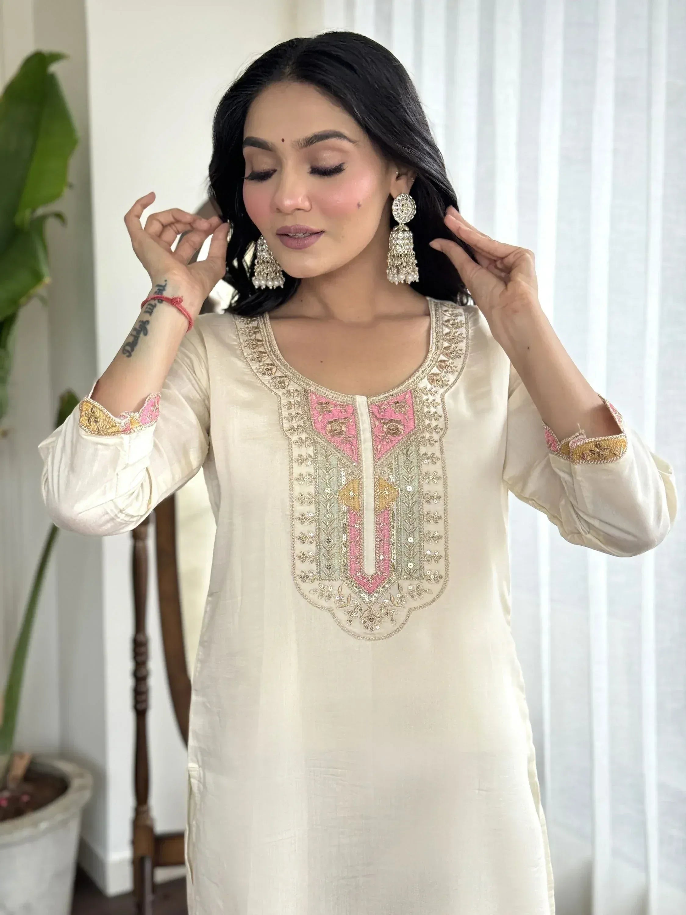 Cream ethnic kurti with pink and gold embroidery, paired with statement earrings for Indian wear