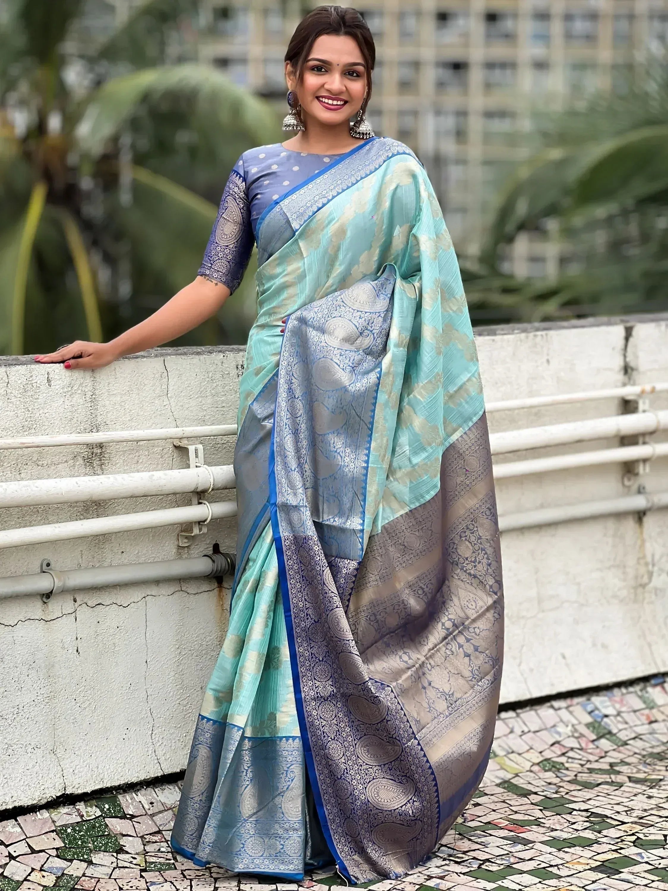Woman in elegant blue and mint designer saree with intricate paisley border, perfect for Indian ethnic wear occasions