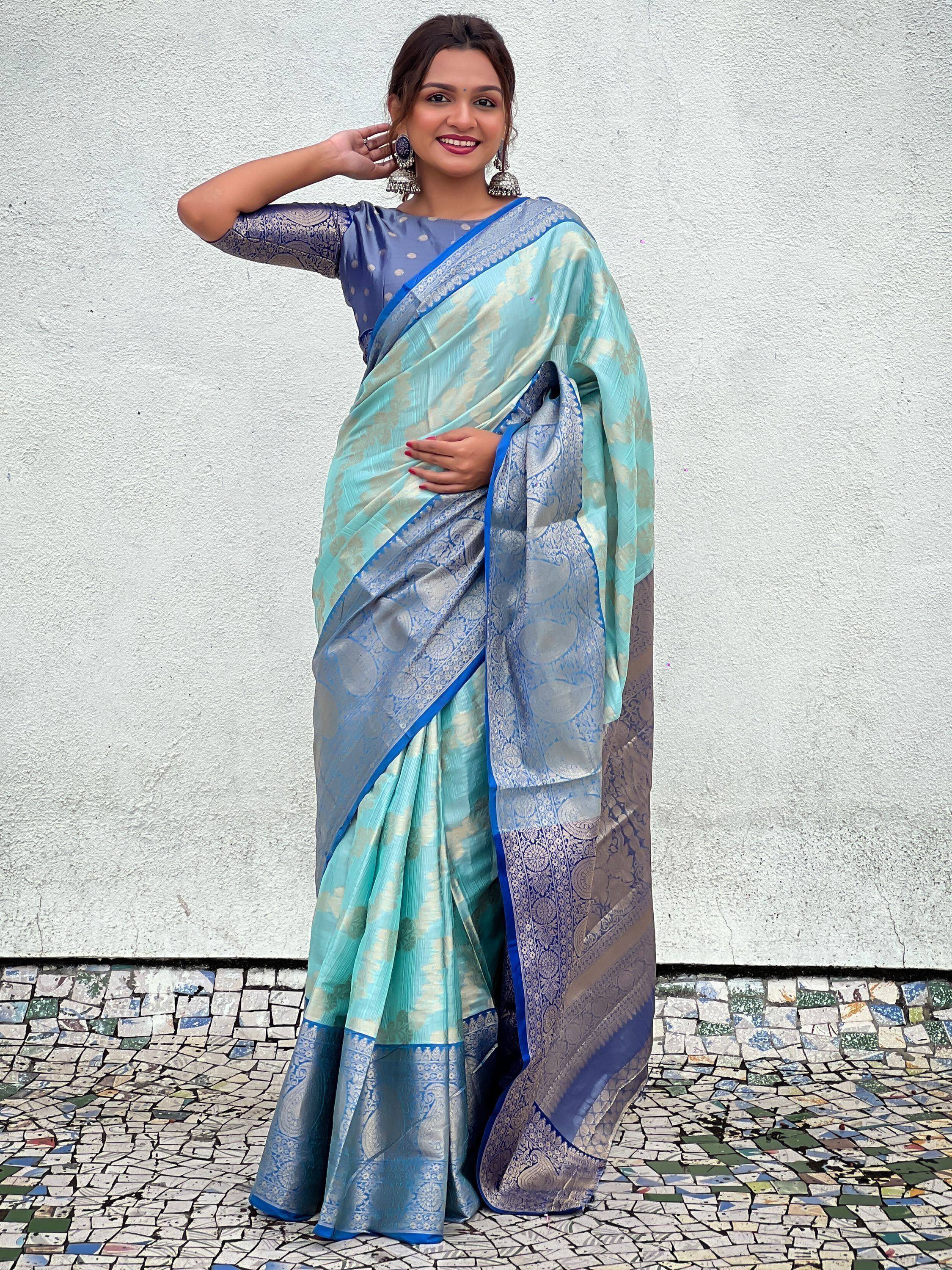 Woman in elegant blue and mint silk saree with intricate gold patterns, paired with matching blouse and jhumka earrings.