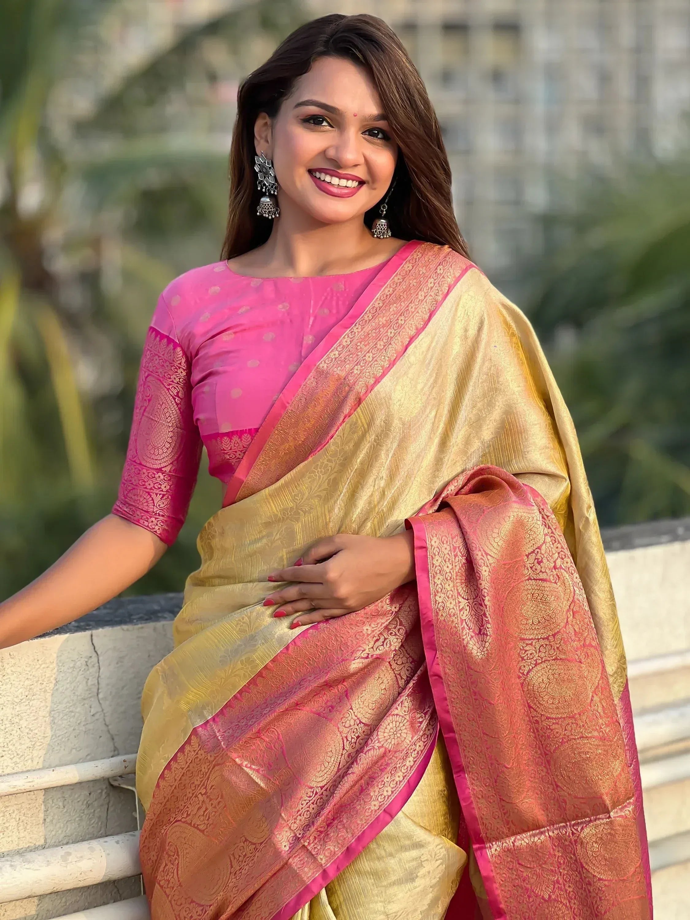 Woman in elegant pink and gold designer saree with intricate patterns, perfect for Indian ethnic occasions