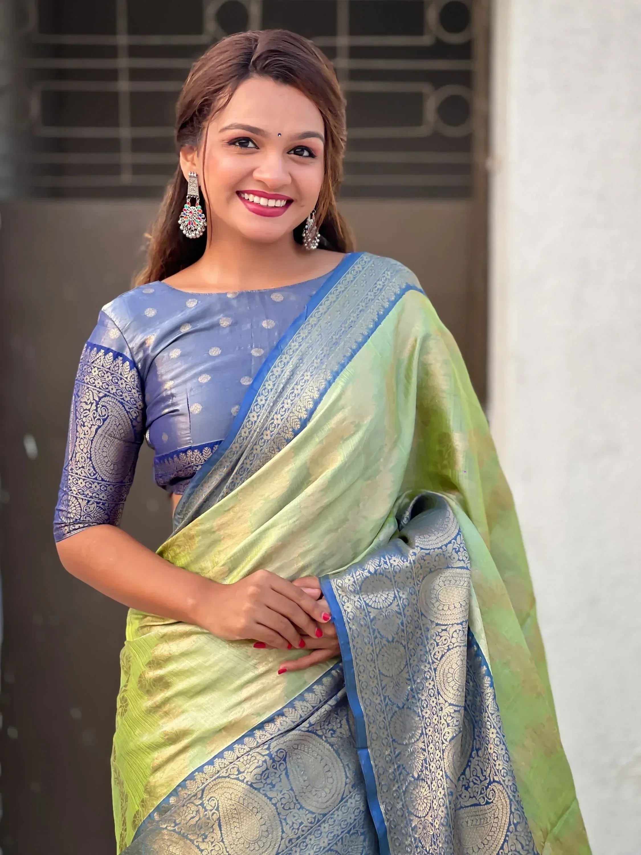 Woman in elegant green and blue designer saree with gold paisley border, perfect for Indian ethnic wear occasions