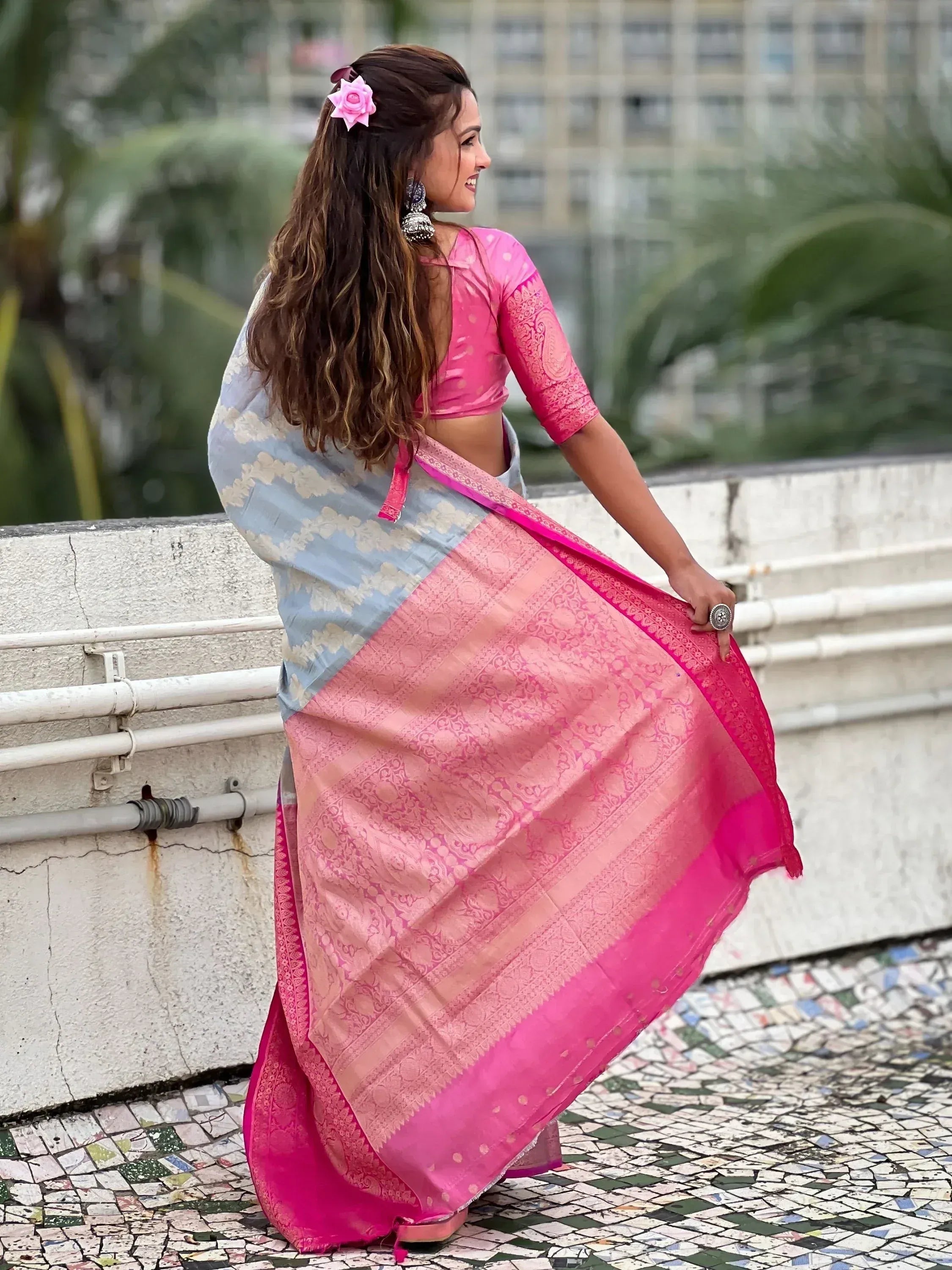 Woman in pink and blue designer saree with floral hair accessory, showcasing ethnic Indian wear