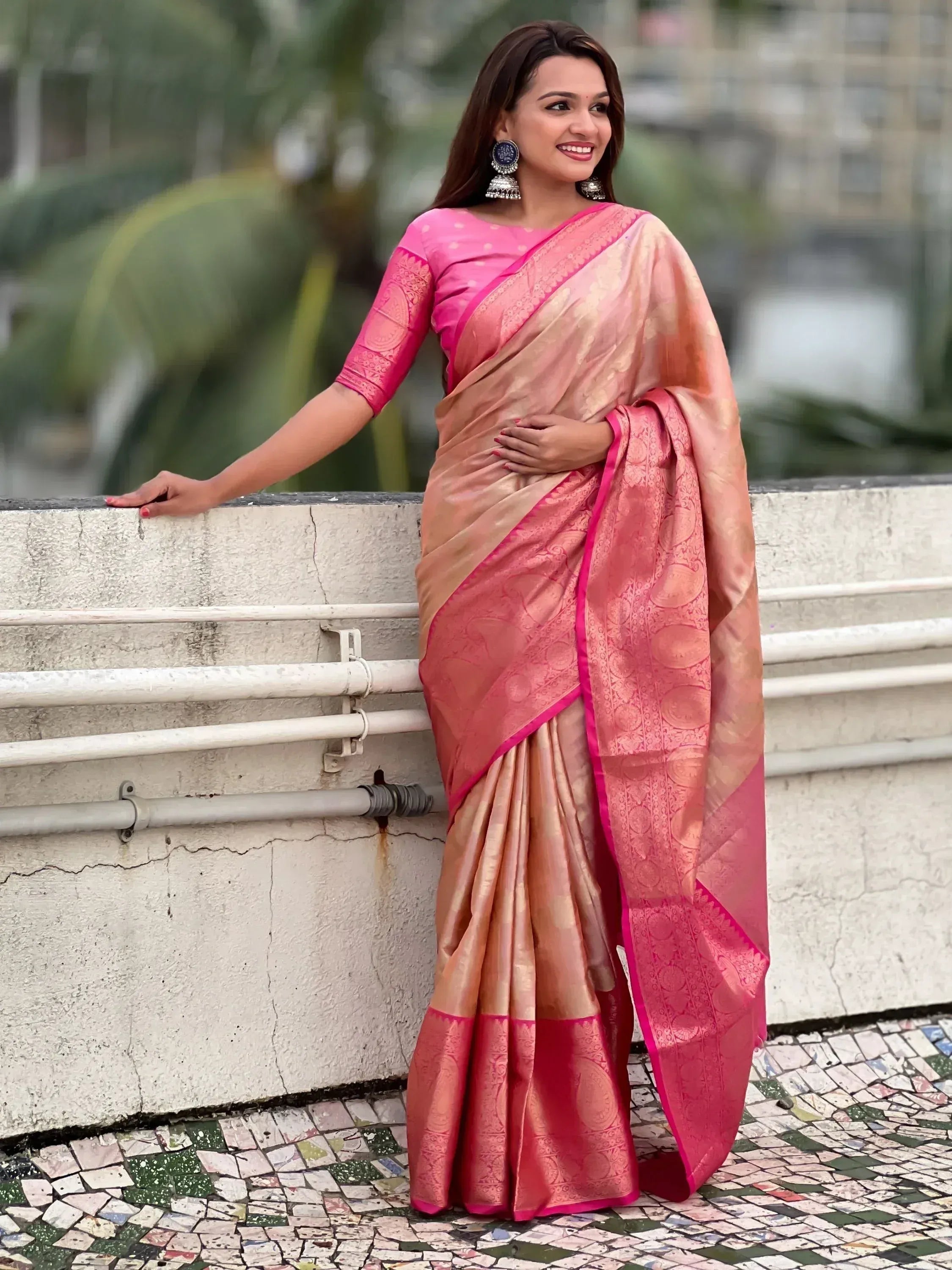 Woman in elegant pink and gold designer saree with intricate patterns, perfect for ethnic occasions