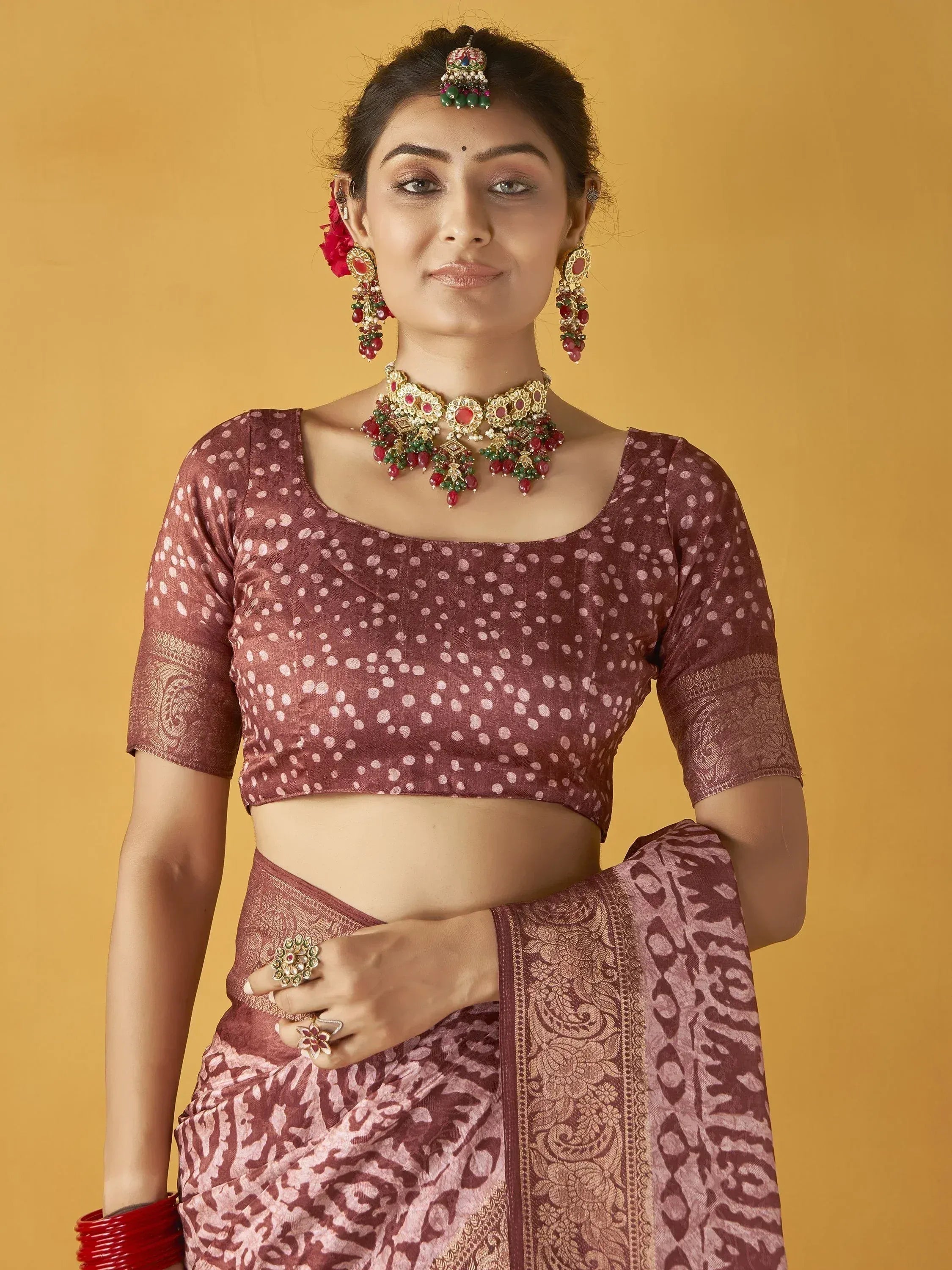 Woman in maroon polka dot blouse and printed saree with traditional jewelry