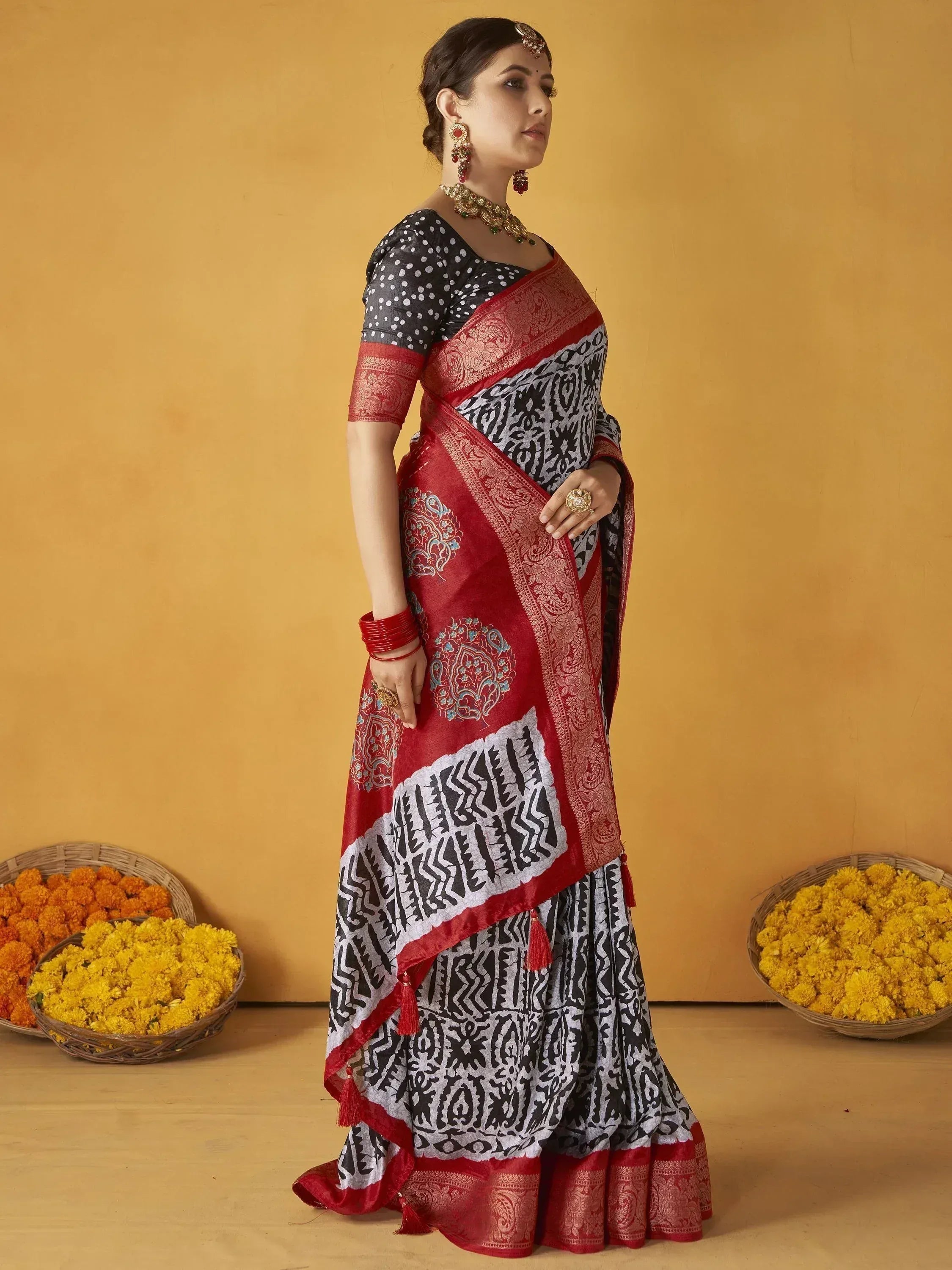 Woman in black and red printed saree with gold jewelry, traditional Indian ethnic wear