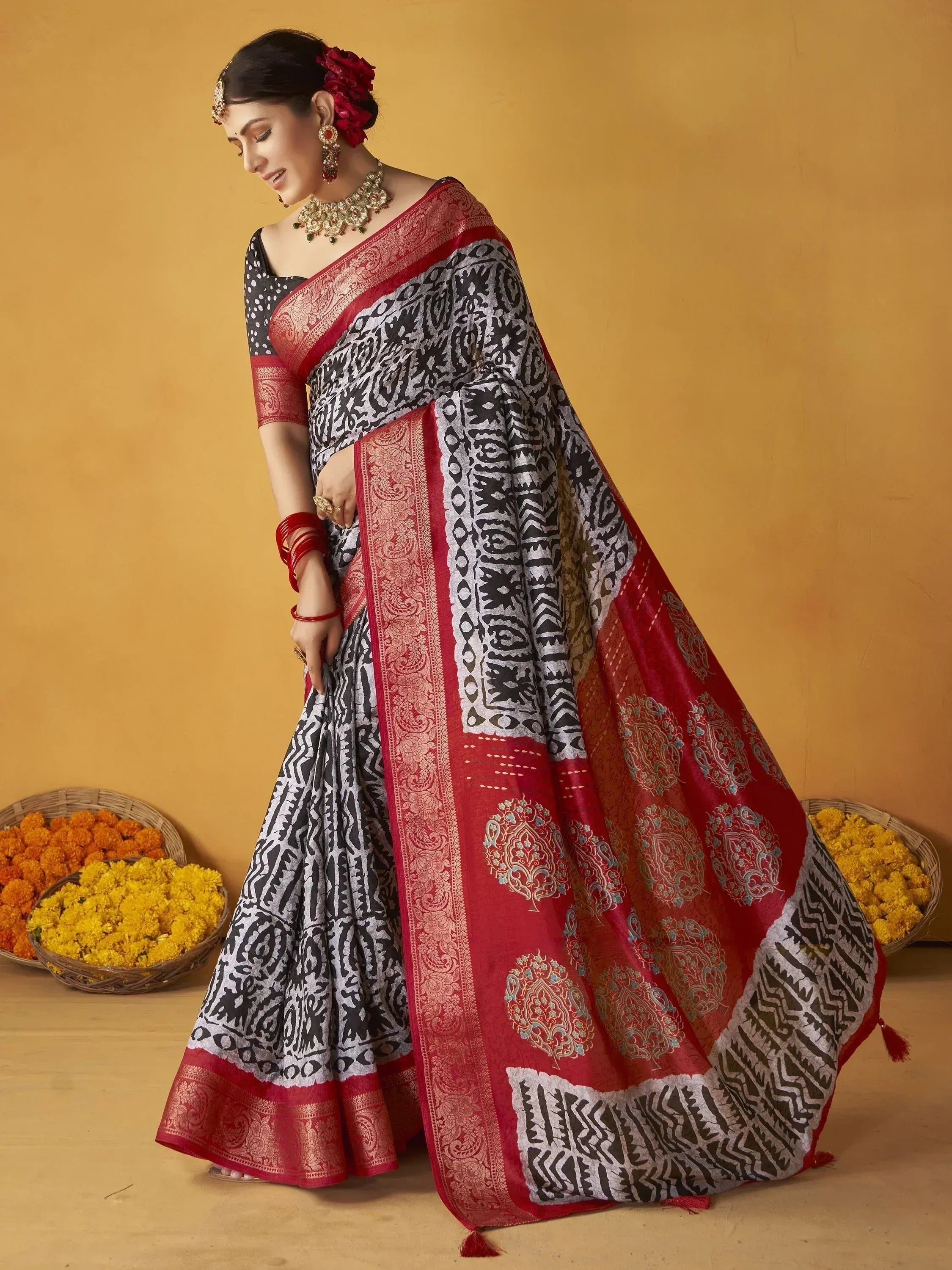 Woman in black and red printed saree with gold border, traditional Indian ethnic wear, floral basket background