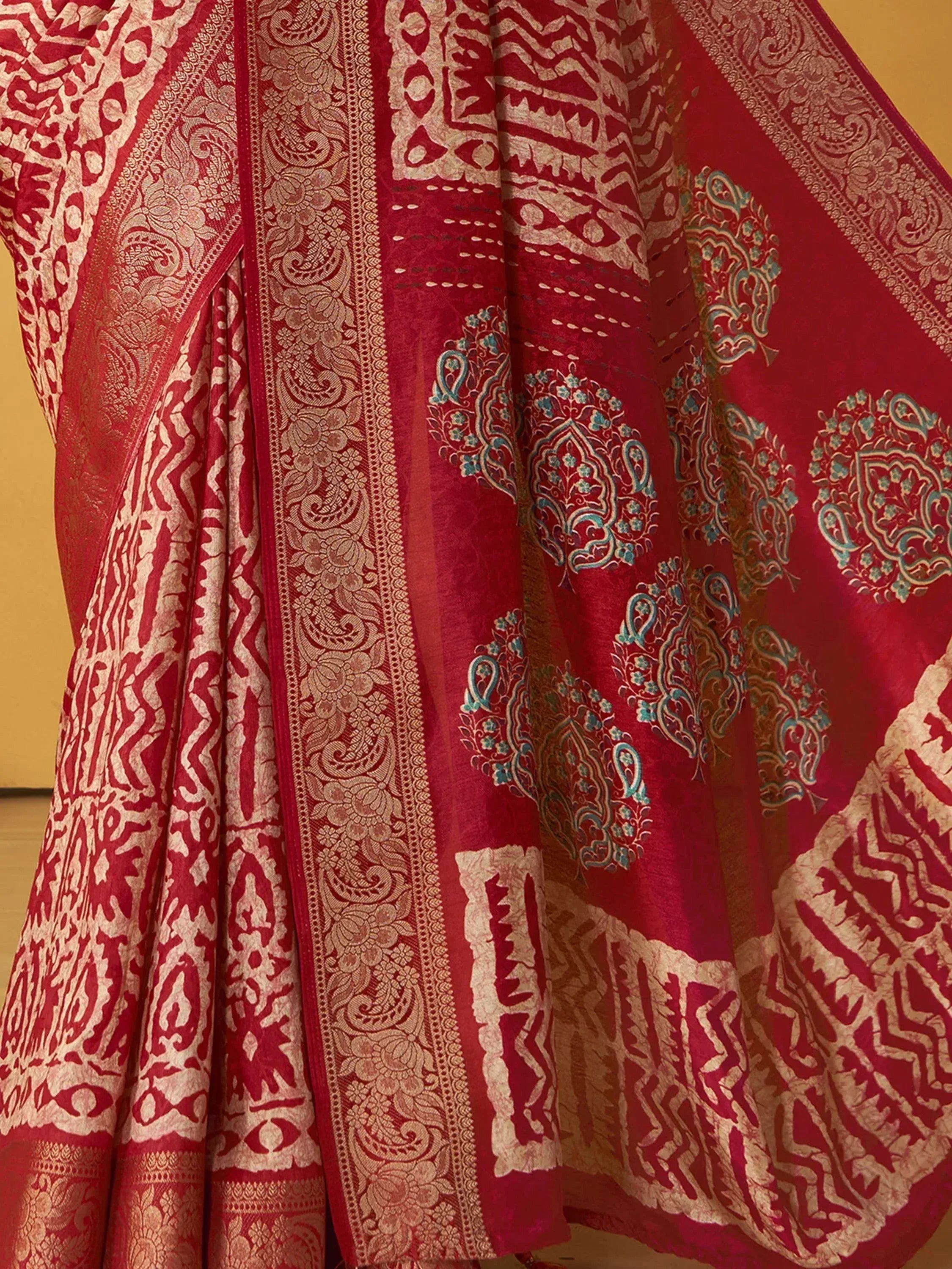 Red ethnic lehenga with intricate gold and turquoise paisley embroidery, perfect for Indian weddings or festive occasions.