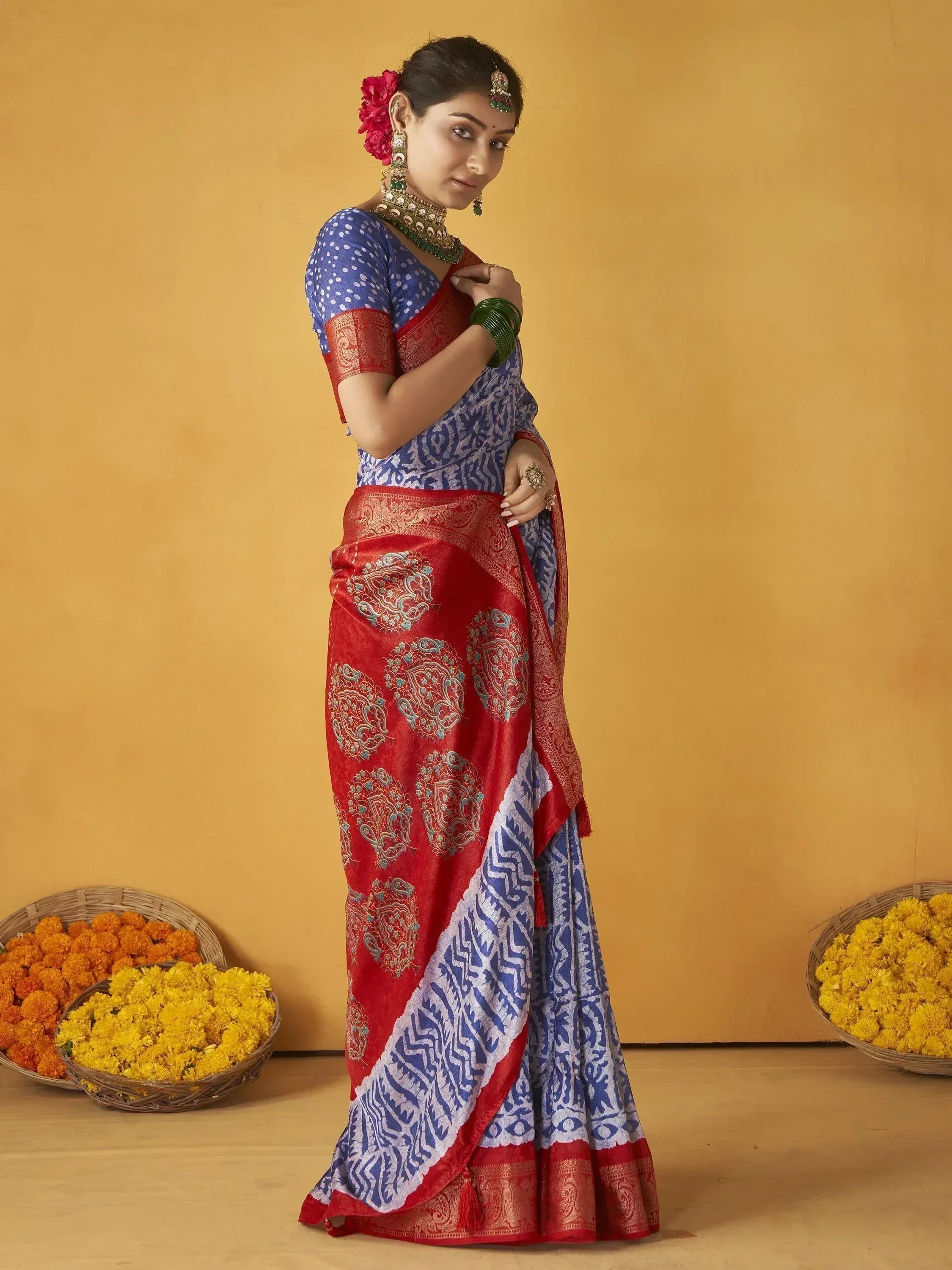 Woman in blue and red printed saree with gold embroidery, traditional Indian ethnic wear, floral baskets background