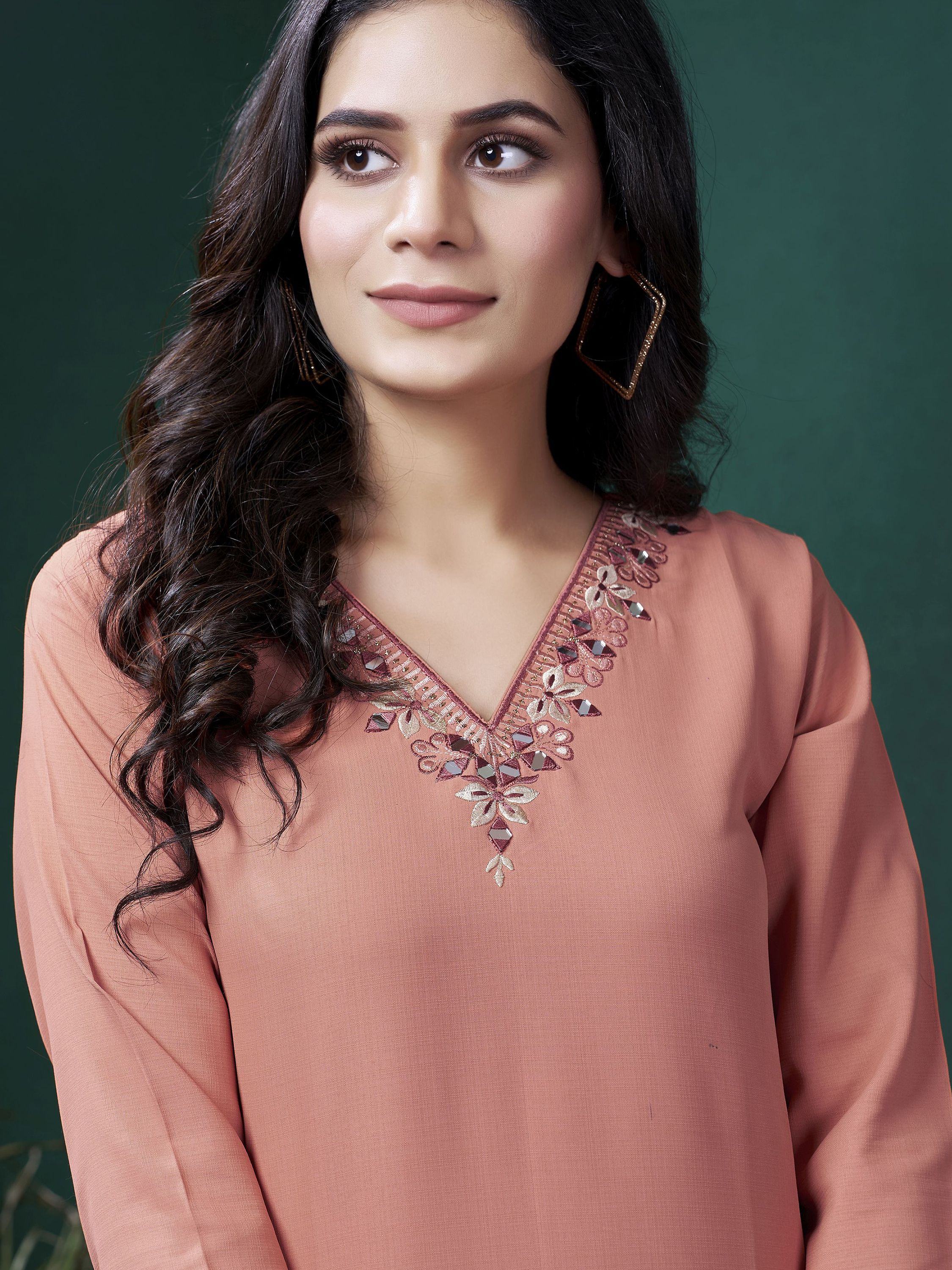 Woman in peach ethnic kurti with floral embroidered V-neck, long sleeves, and wavy hair