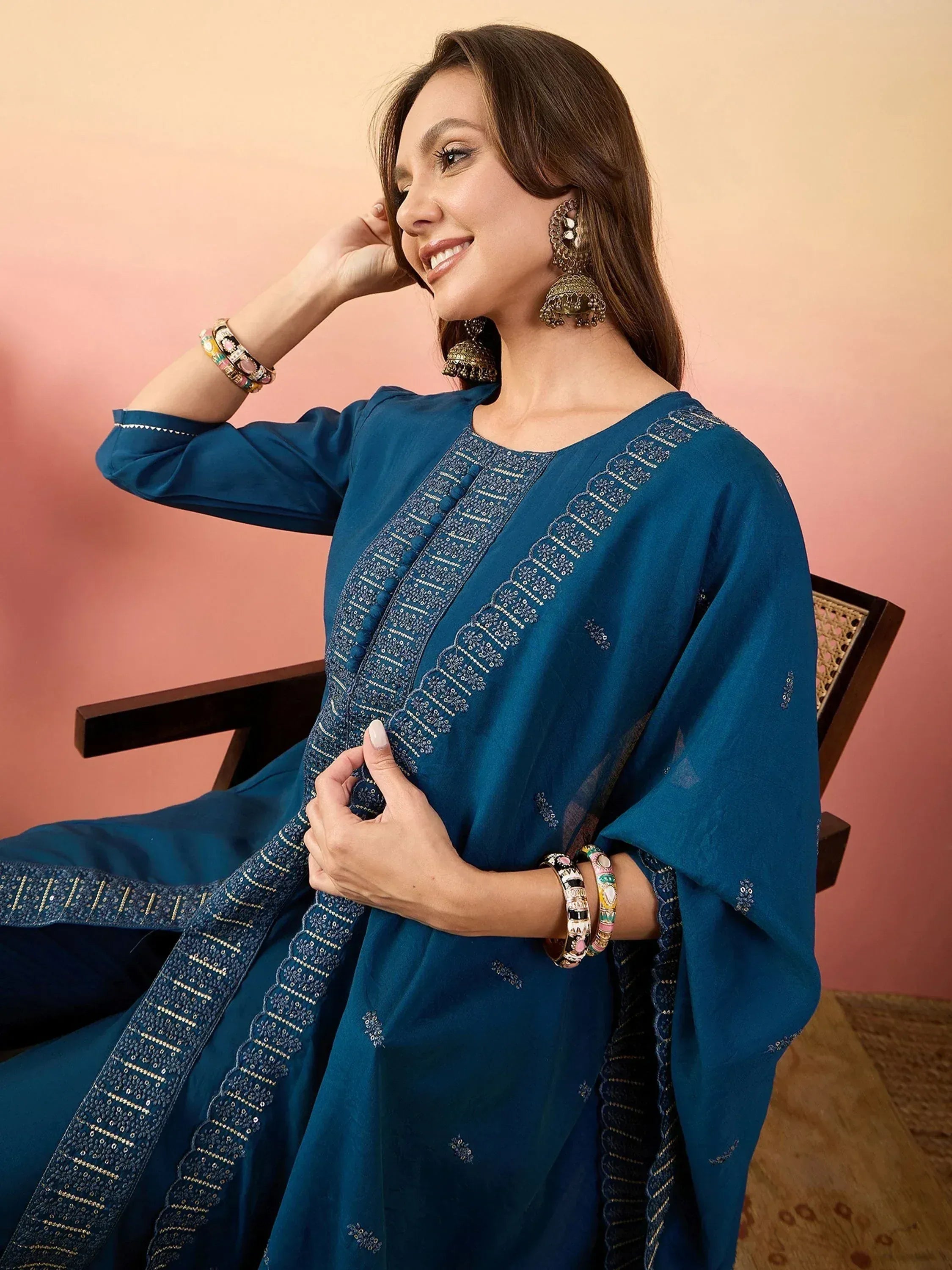 Woman in elegant teal embroidered salwar kameez with jhumka earrings and bangles, showcasing Indian ethnic wear.
