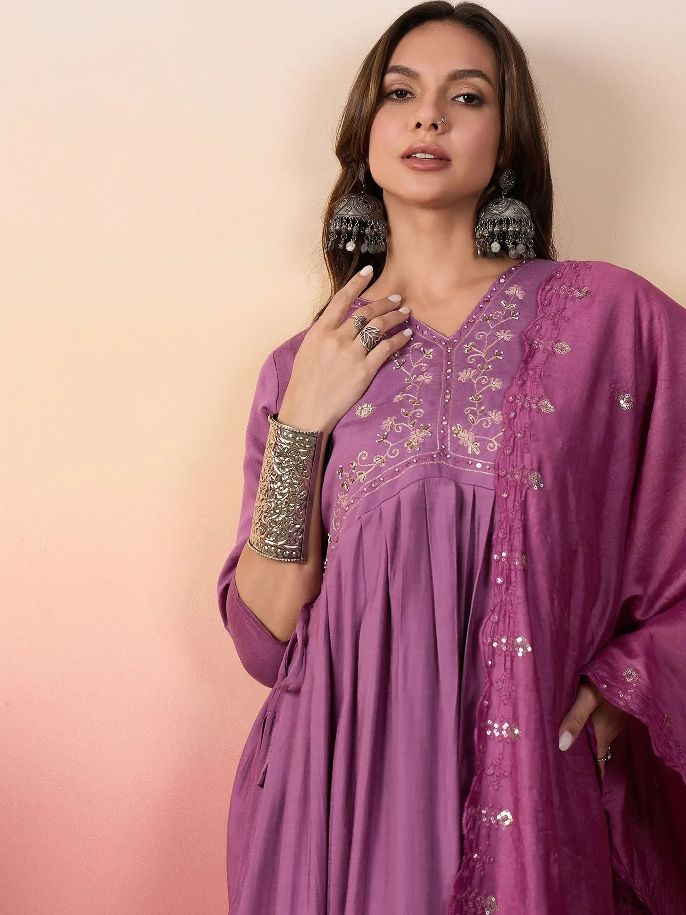 Purple ethnic gown with gold embroidery, paired with traditional jhumka earrings and bangles for festive wear