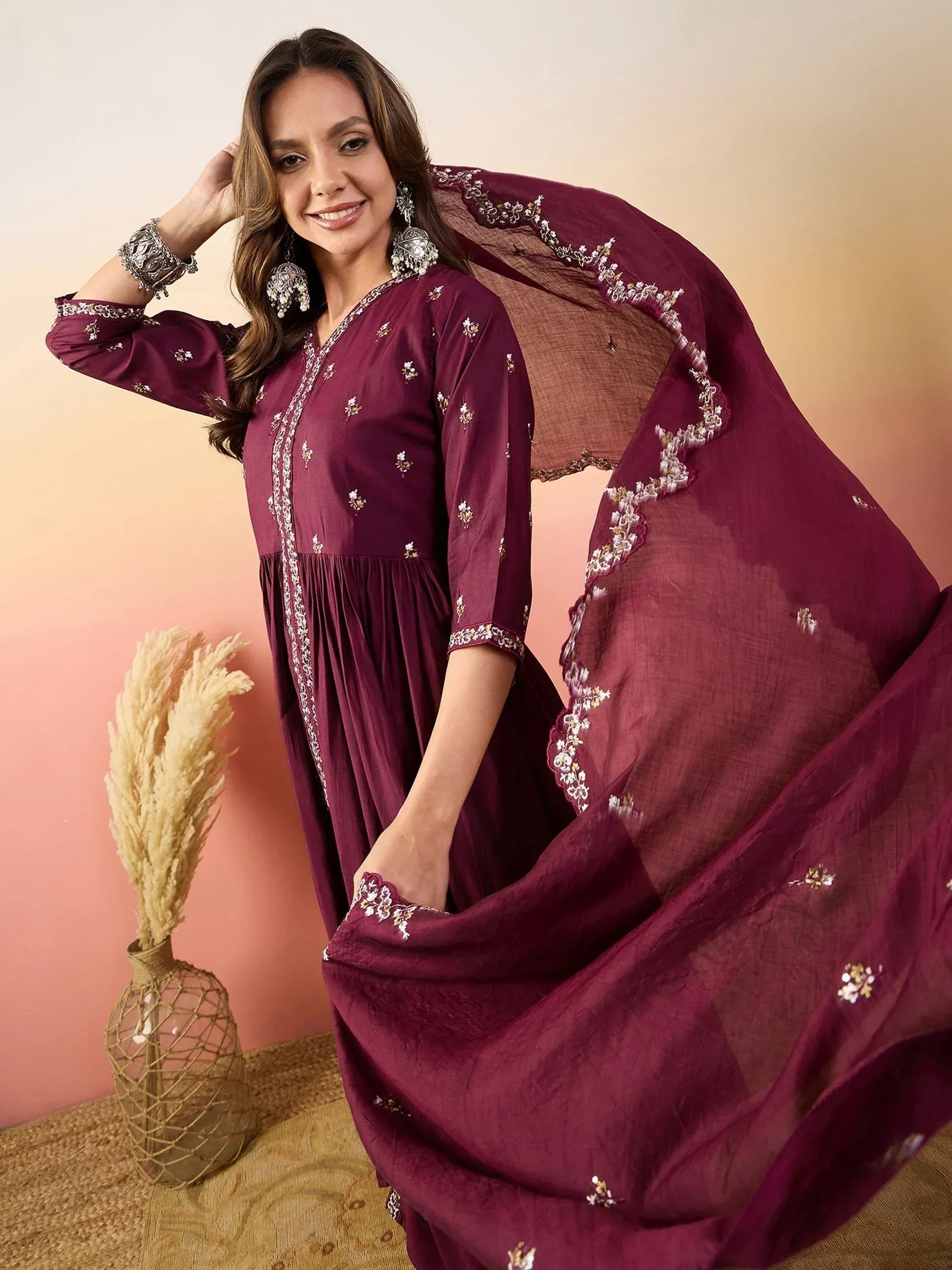 Elegant maroon ethnic gown with floral embroidery and matching dupatta, styled with traditional jewelry