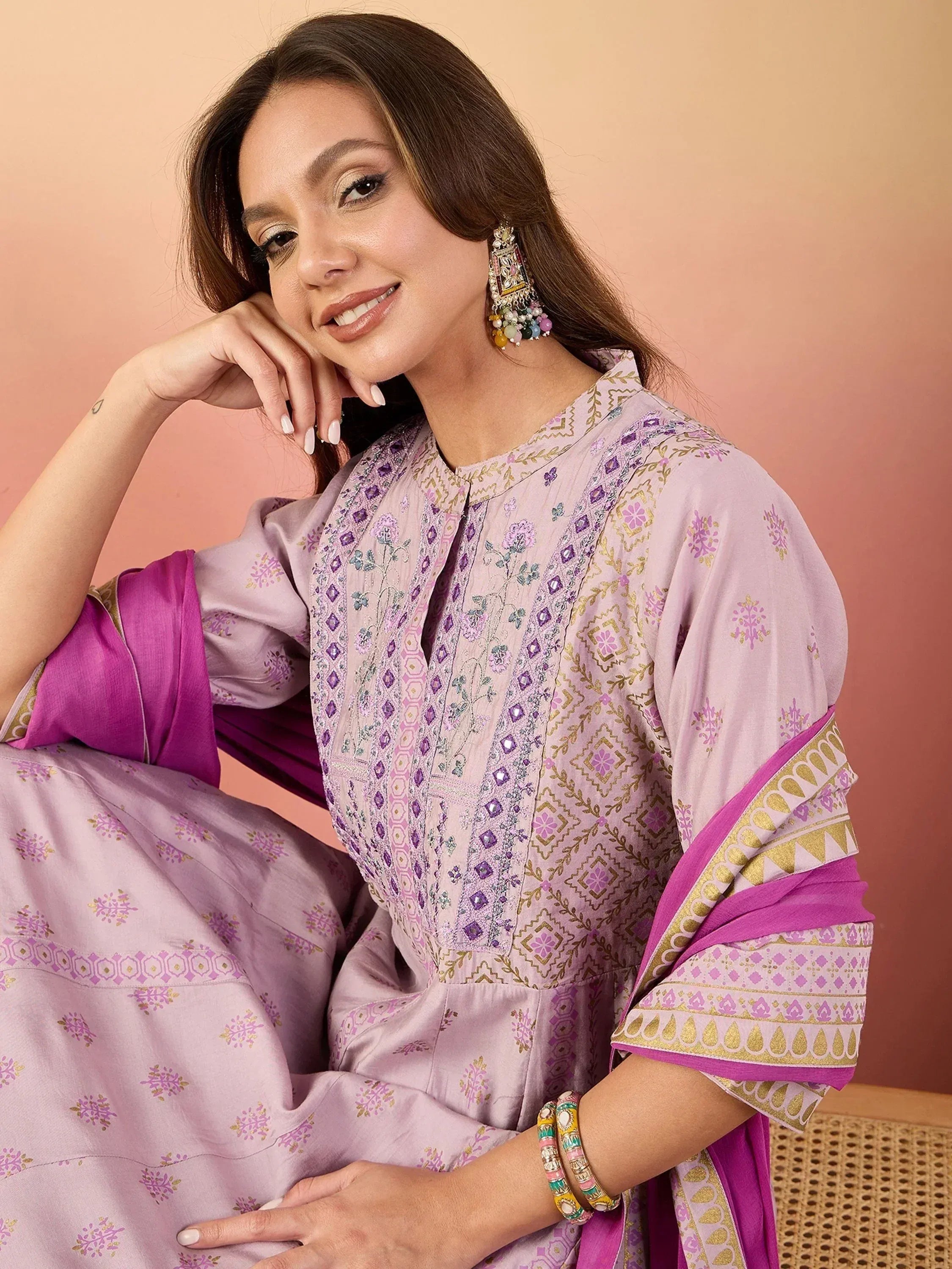 Woman in lavender embroidered salwar kameez with purple dupatta, floral patterns, and gold detailing