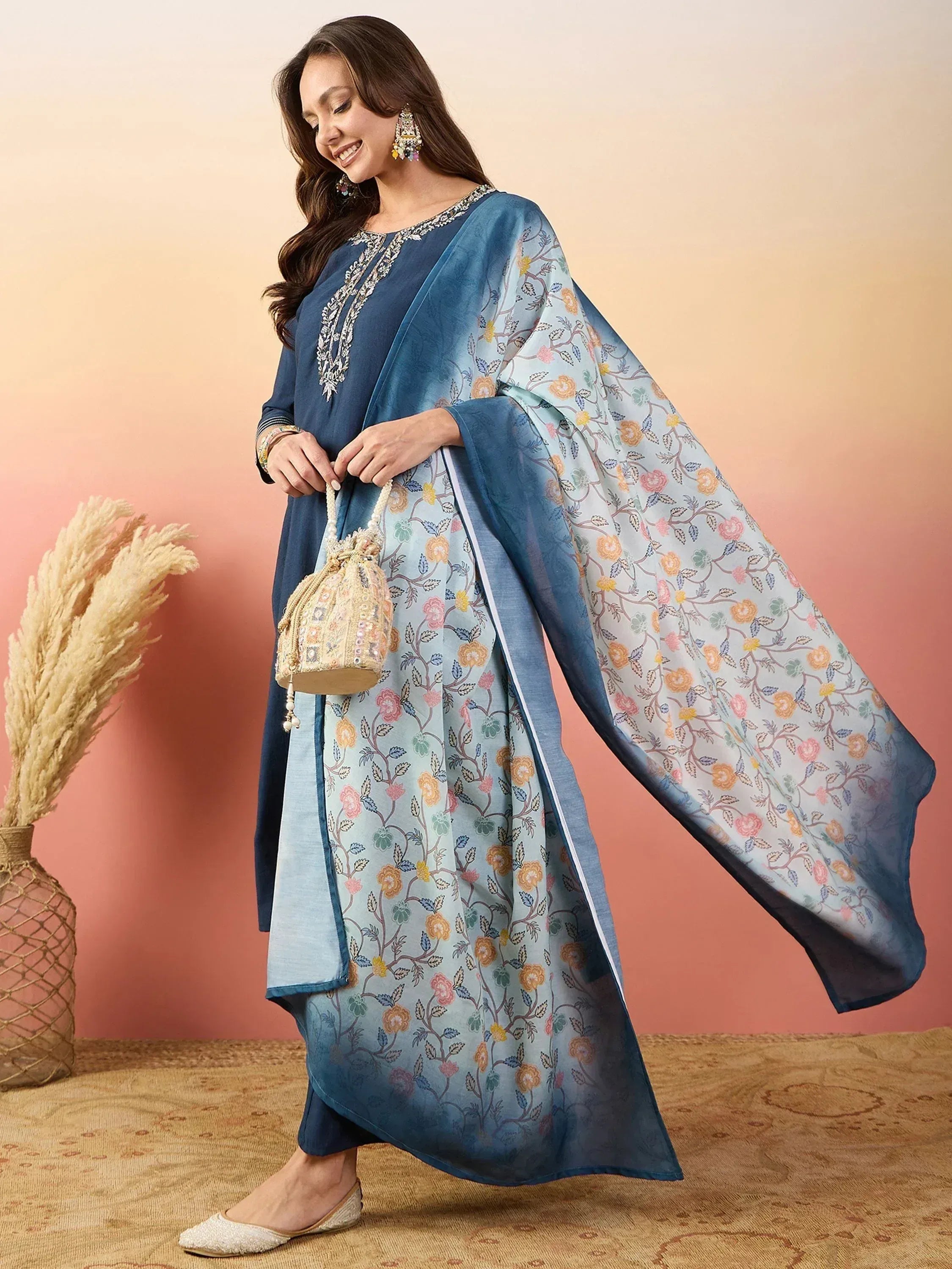 Blue floral printed Indian ethnic salwar kameez with embroidered neckline and dupatta, paired with embellished potli bag