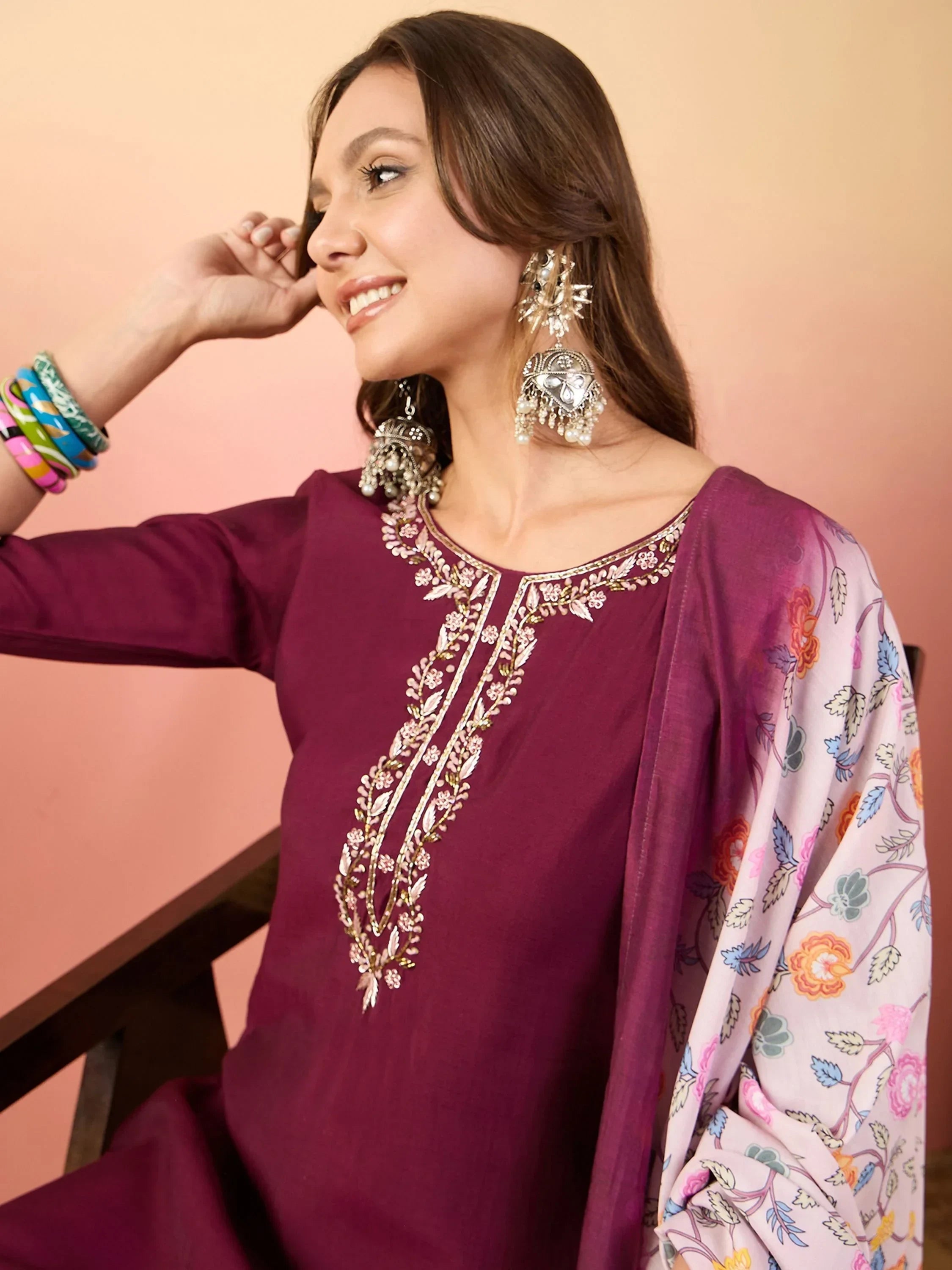 Woman in maroon embroidered salwar kameez with floral dupatta and statement earrings