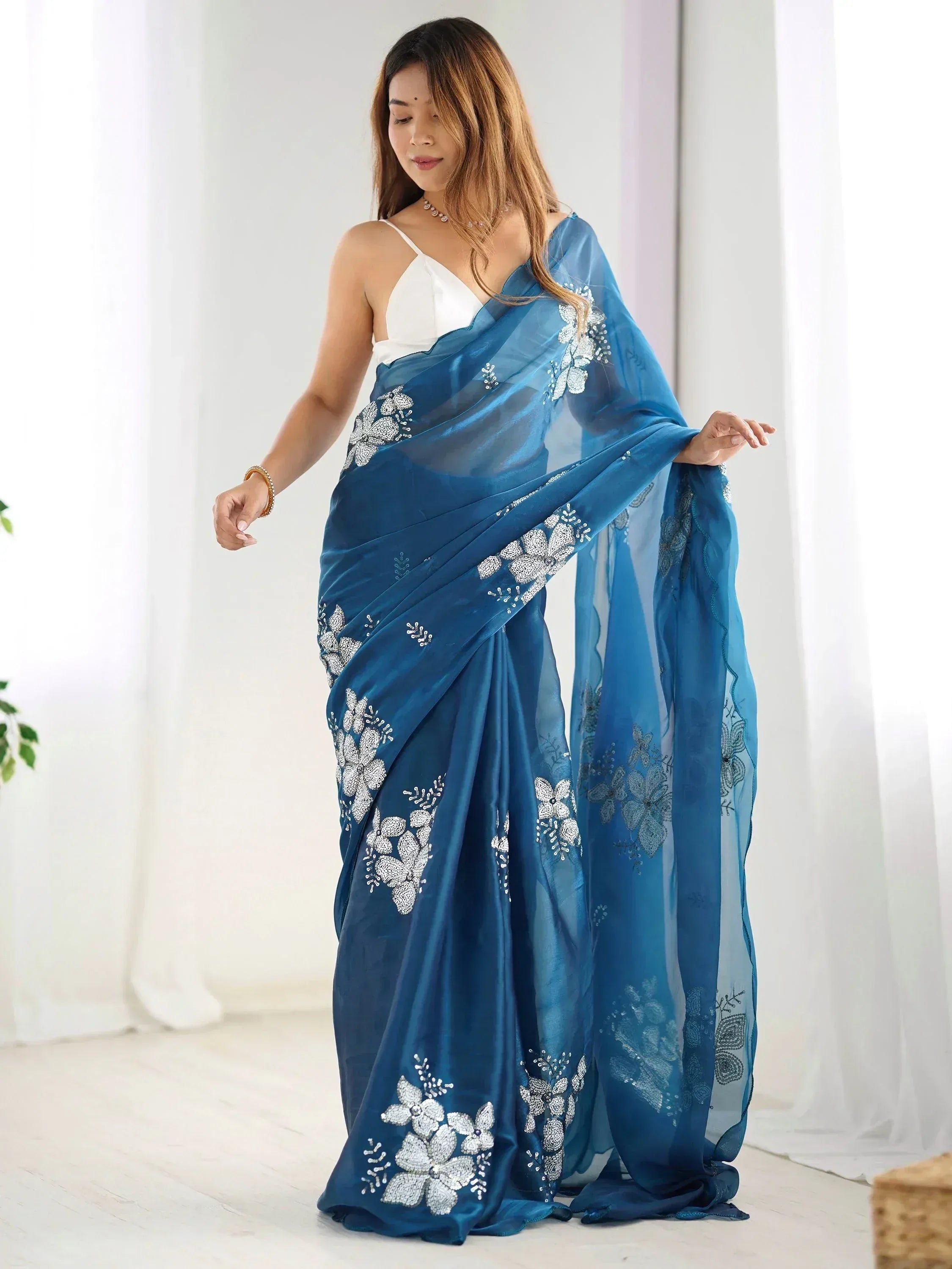 Blue embroidered saree with floral embellishments, styled with white blouse for ethnic wear