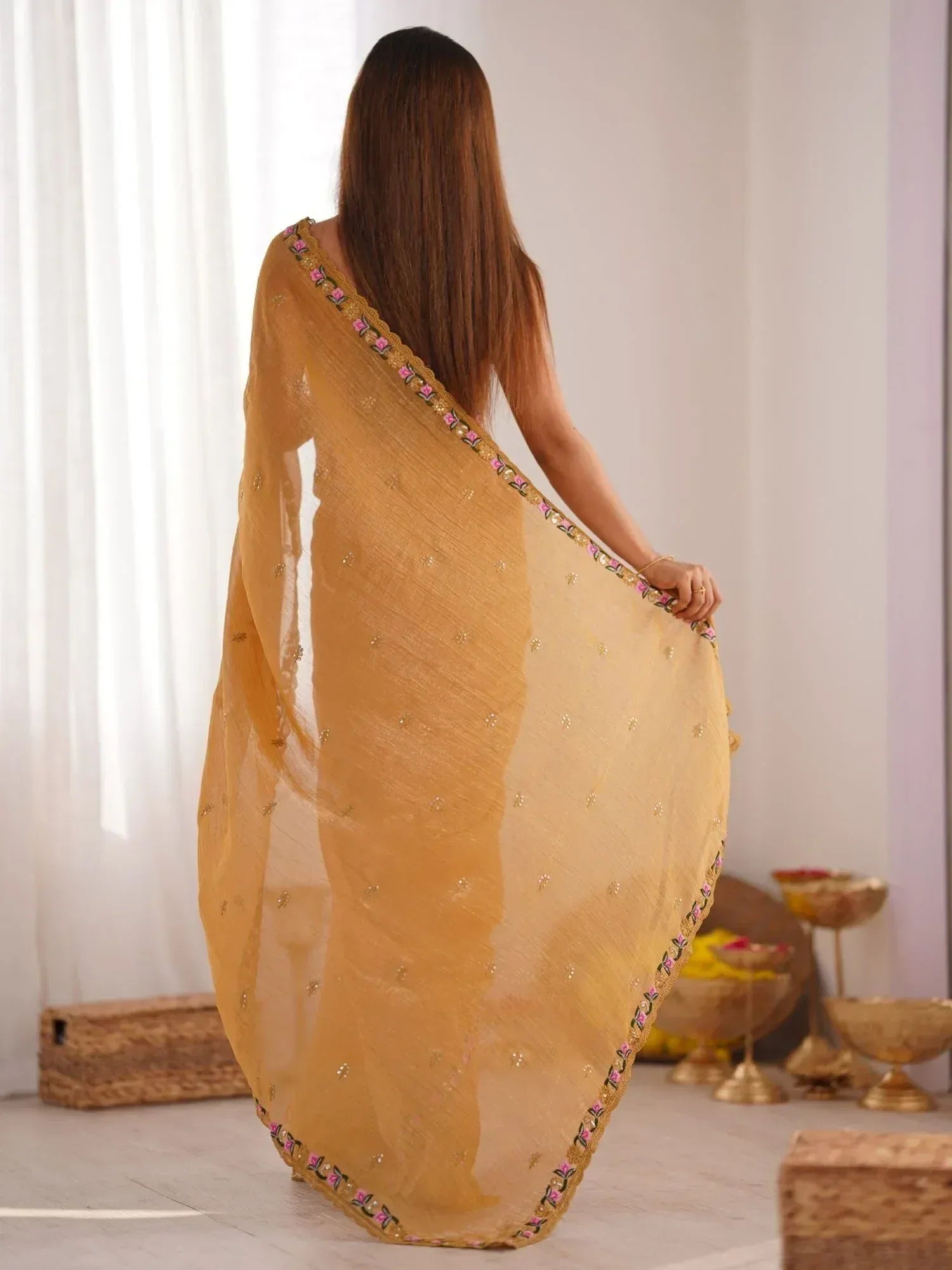 Woman in mustard yellow embroidered saree with floral border, back view, ethnic wear