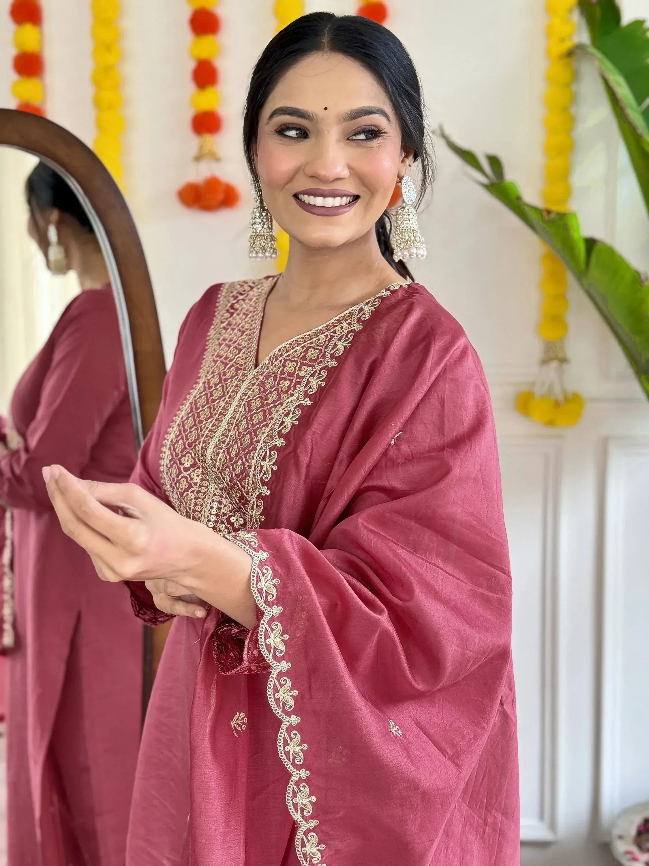 Woman in maroon ethnic kurta with gold embroidery, festive decor, traditional Indian wear