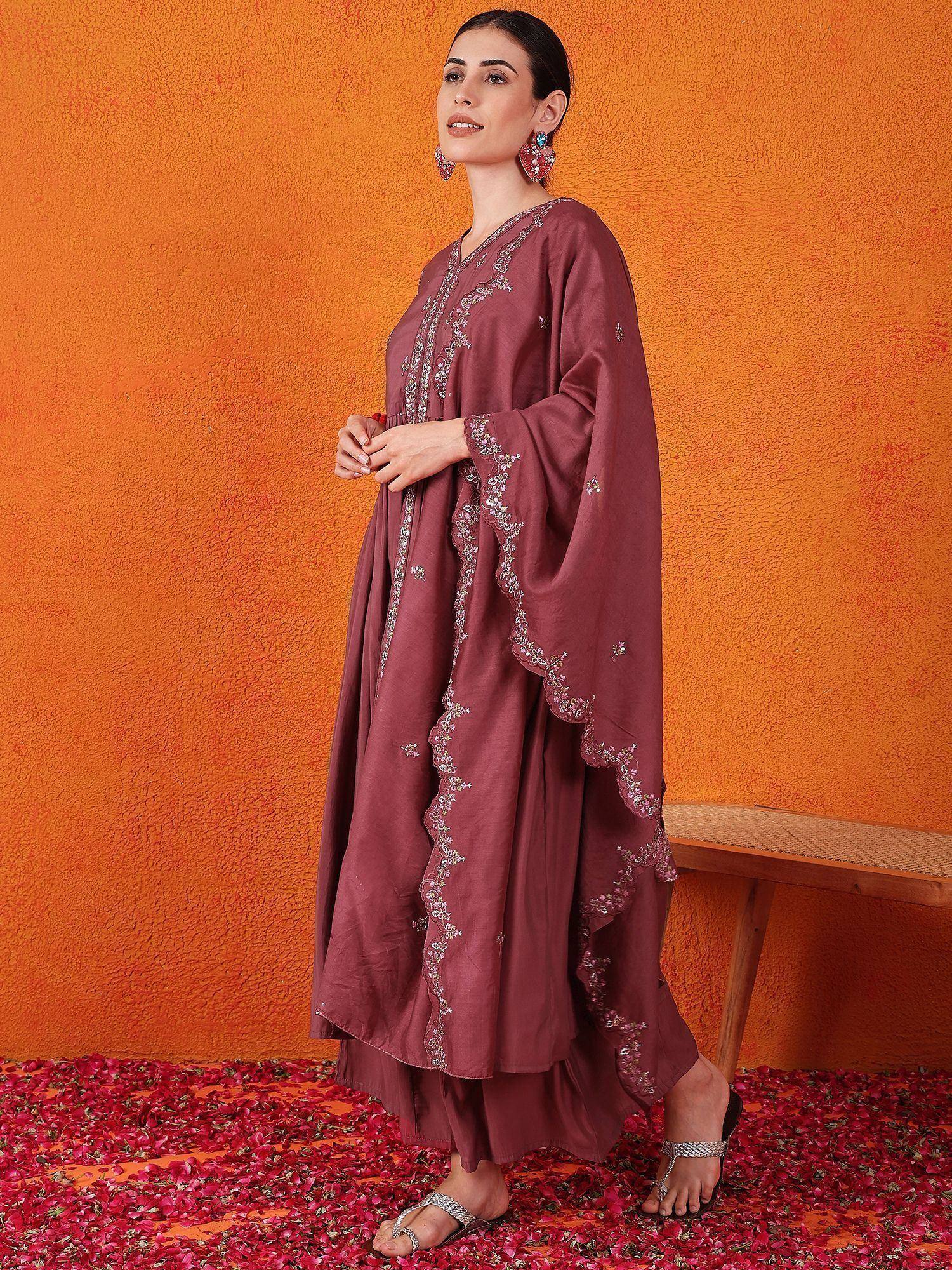 Maroon embroidered ethnic gown with flared sleeves, styled with silver sandals against orange wall and rose petals