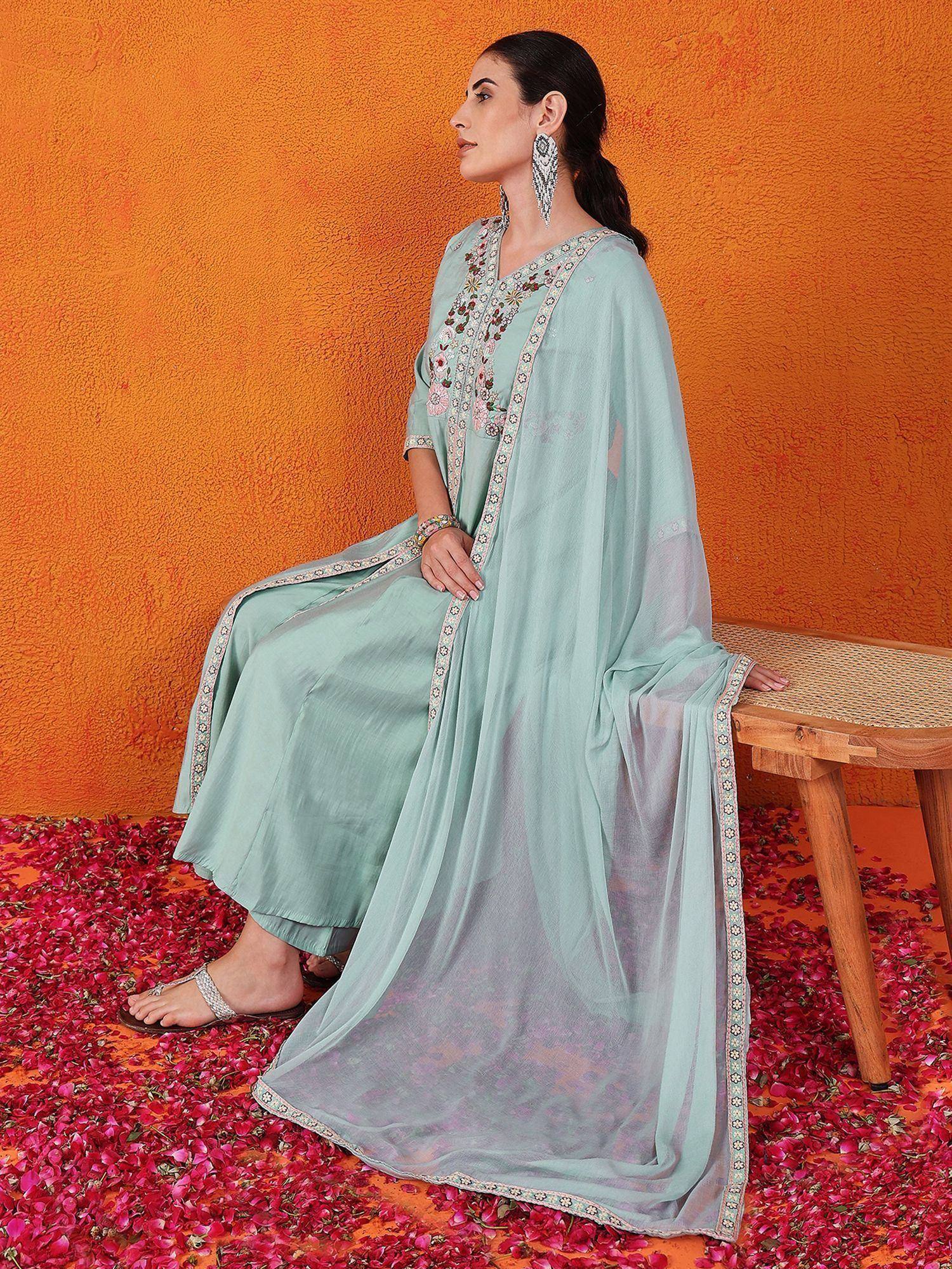 Mint green embroidered salwar kameez with sheer dupatta, floral detailing, and rose petals on orange backdrop