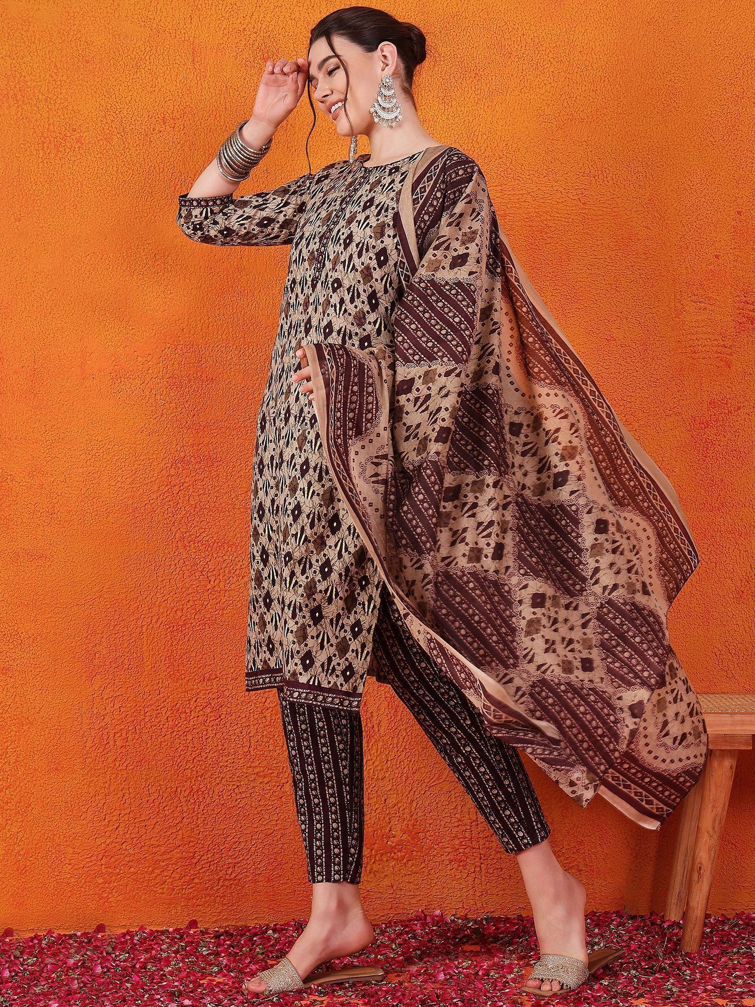 Woman in brown and black printed salwar kameez with dupatta, silver jewelry, orange background