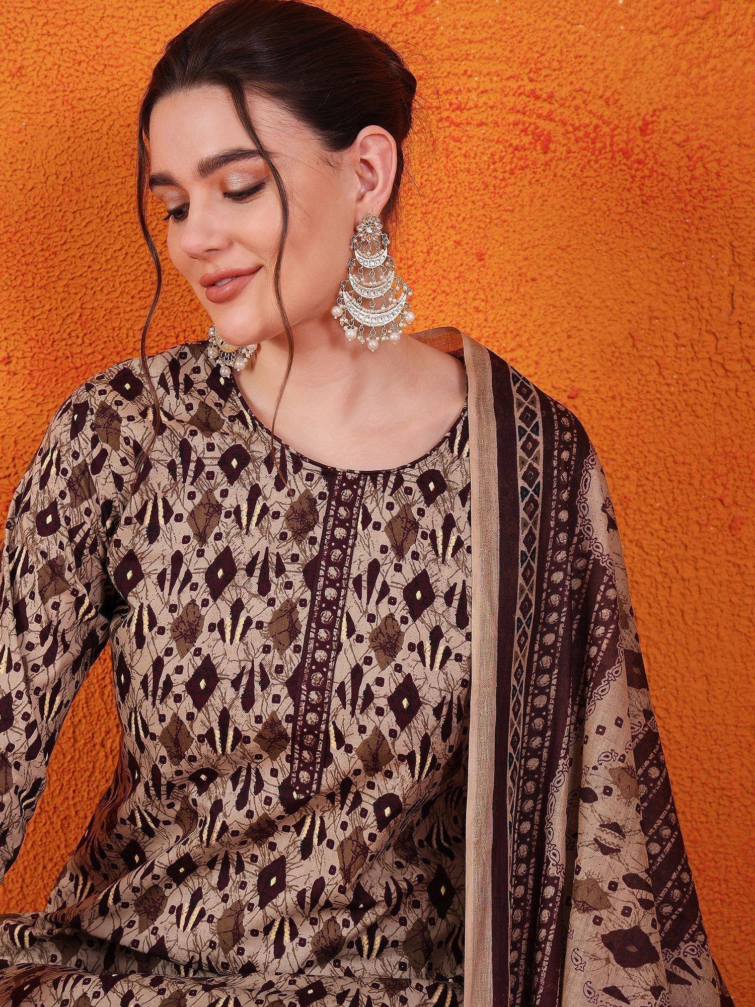 Woman in elegant ethnic salwar kameez with geometric print, paired with statement jhumka earrings against orange backdrop.
