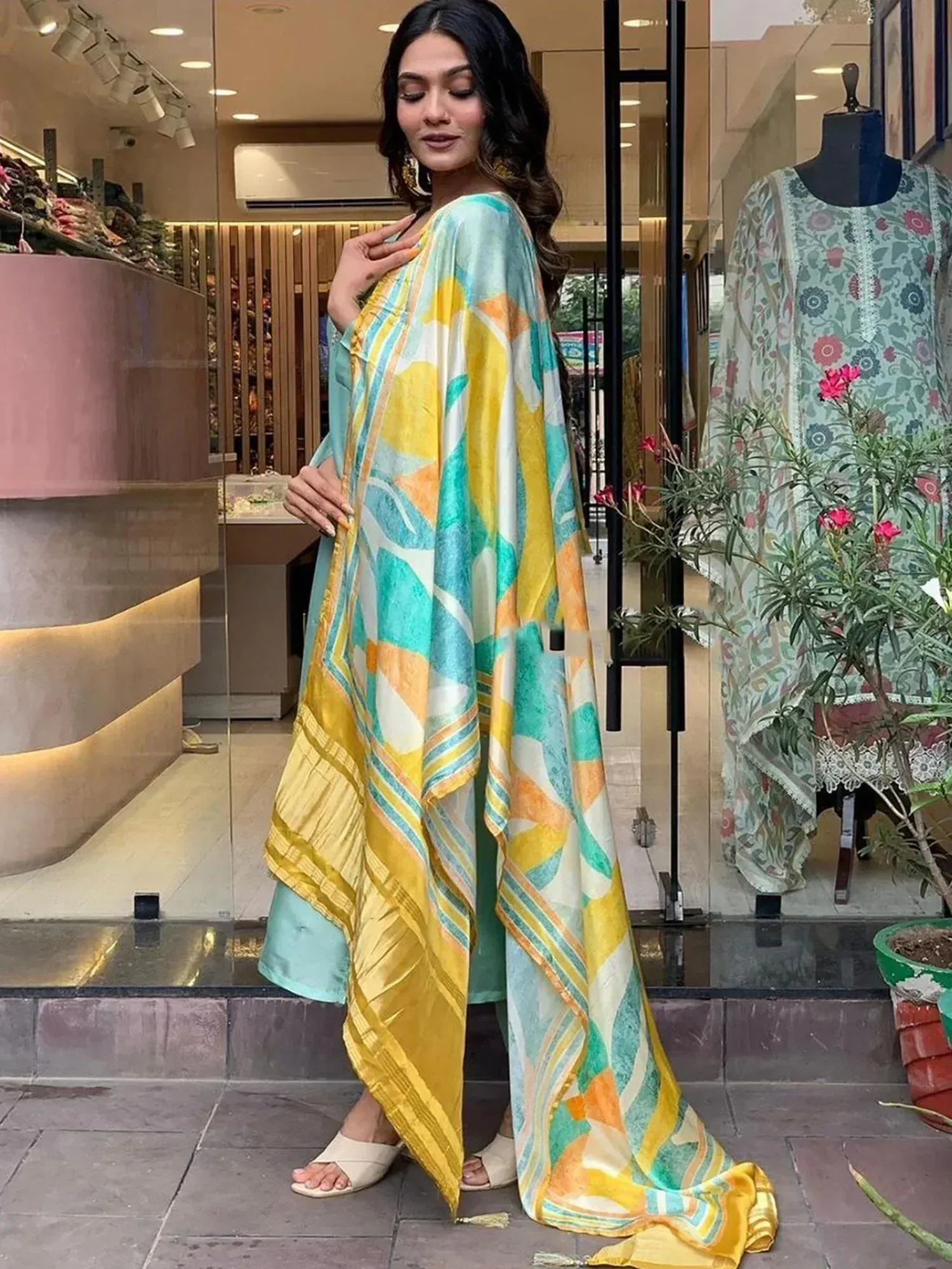 Woman in vibrant yellow and teal printed ethnic gown with matching dupatta, stylish Indian wear