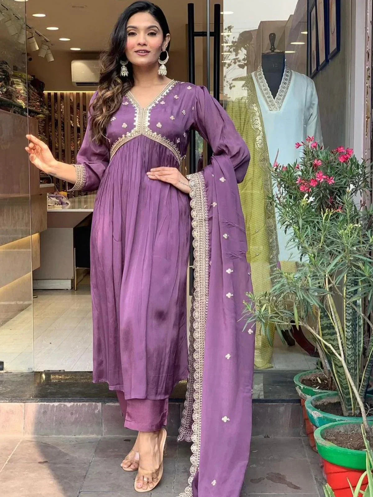 Woman in purple embroidered salwar kameez with dupatta, standing at store entrance